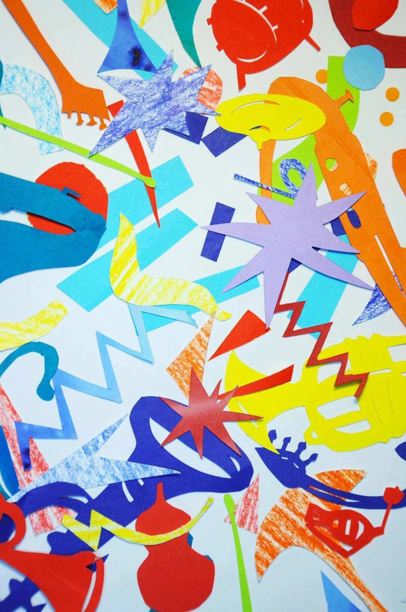 Colorful paper cut-outs of stars, circles, and abstract shapes scattered on a white background.