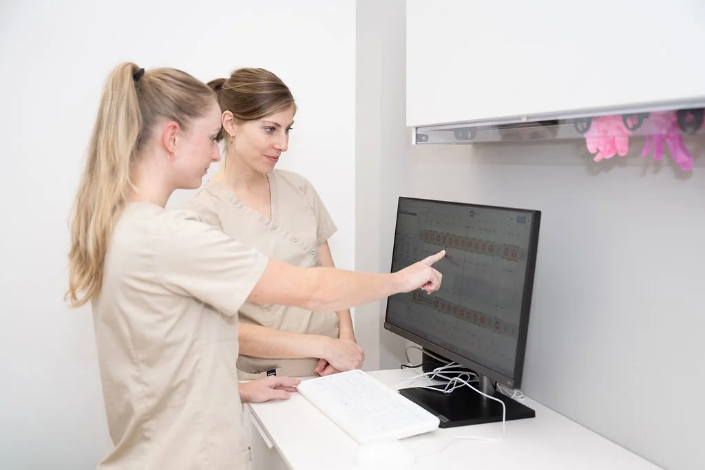 Twee mondhygiënisten van Mondzorg Voorne in Hellevoetsluis en Oostvoorne bekijken samen diagrammen op een computerscherm in de praktijk.