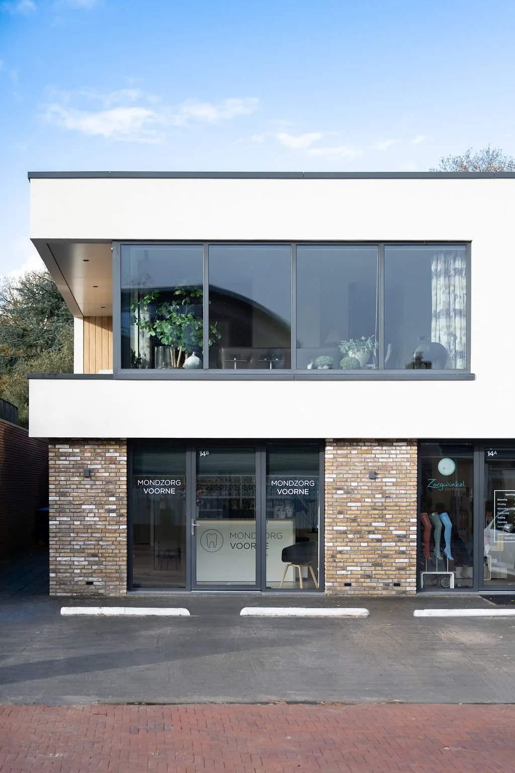 Moderne buitenzijde van Mondzorg Voorne in Oostvoorne, met duidelijke ingang en parkeergelegenheid direct voor de mondhygiënistpraktijk.