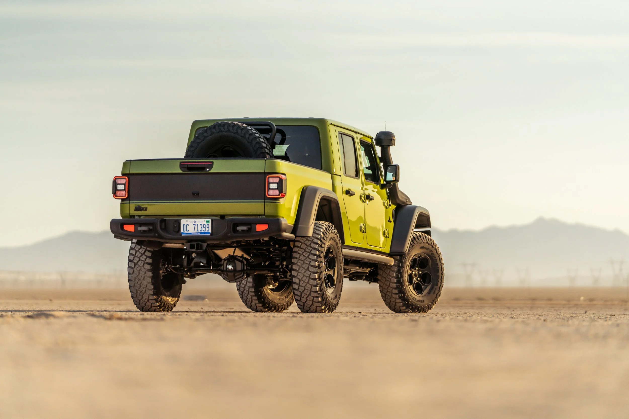 A green off-road vehicle with large tires in a desert landscape.