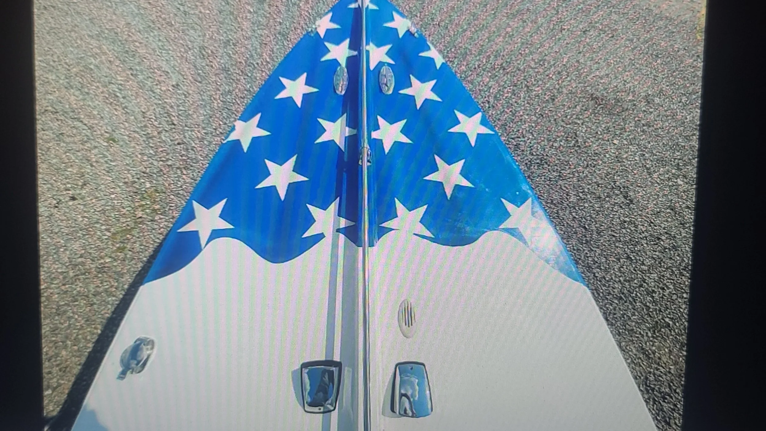 Close-up of a 4th of July or patriotic themed cooler with an American flag design on the lid, on a paved surface.