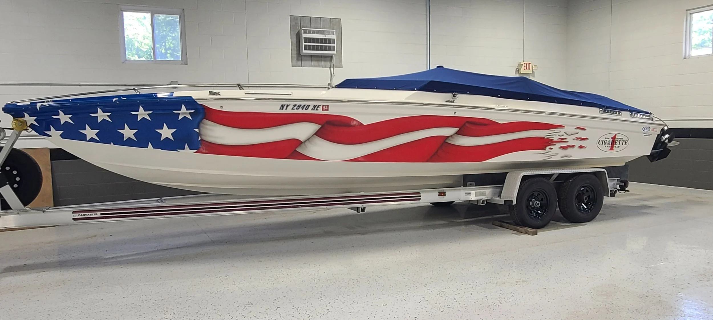 Speedboat with American flag-themed graphics parked on a trailer inside a garage.