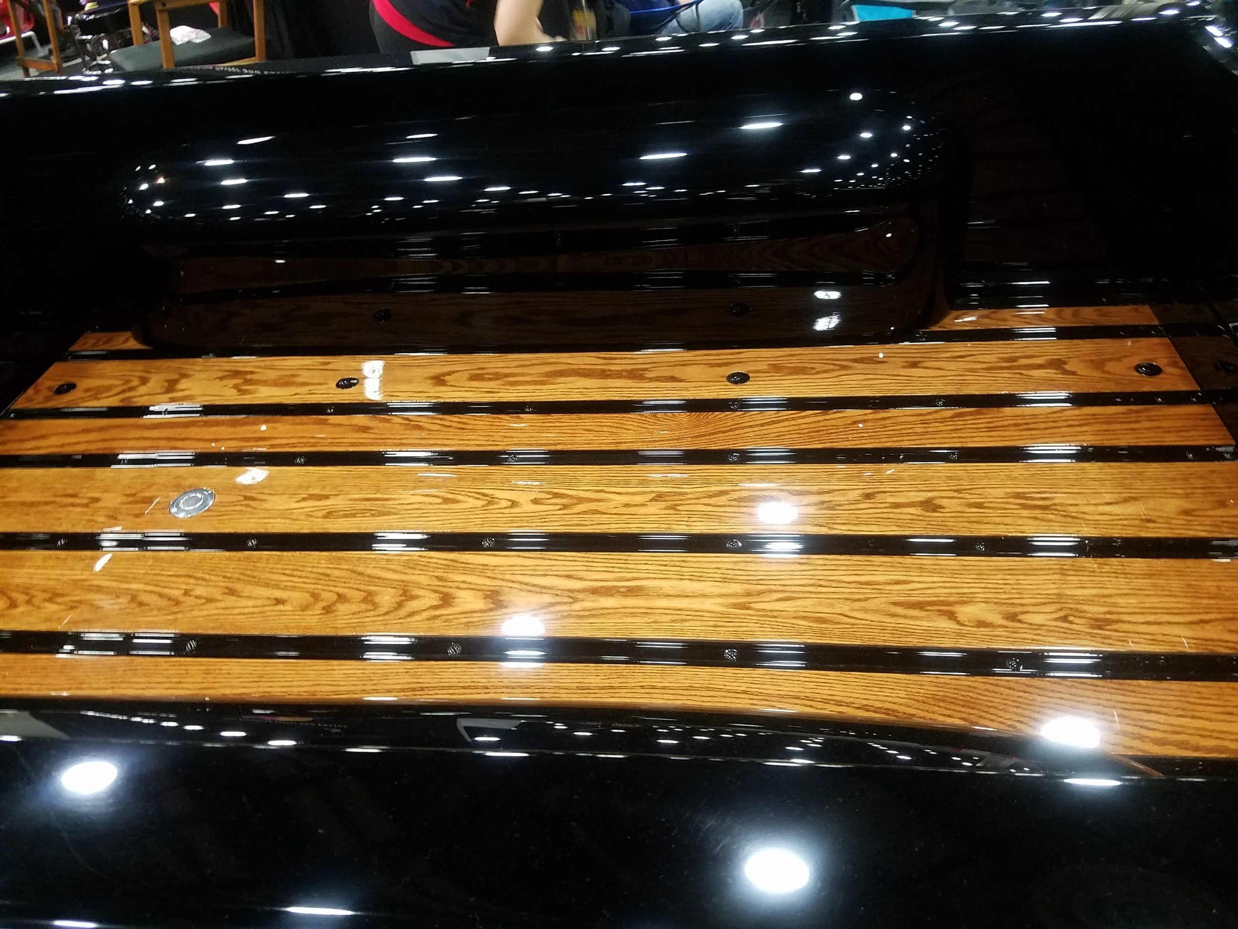 Close-up of a wooden boat deck with black accents and shiny finish, possibly at a boat show.