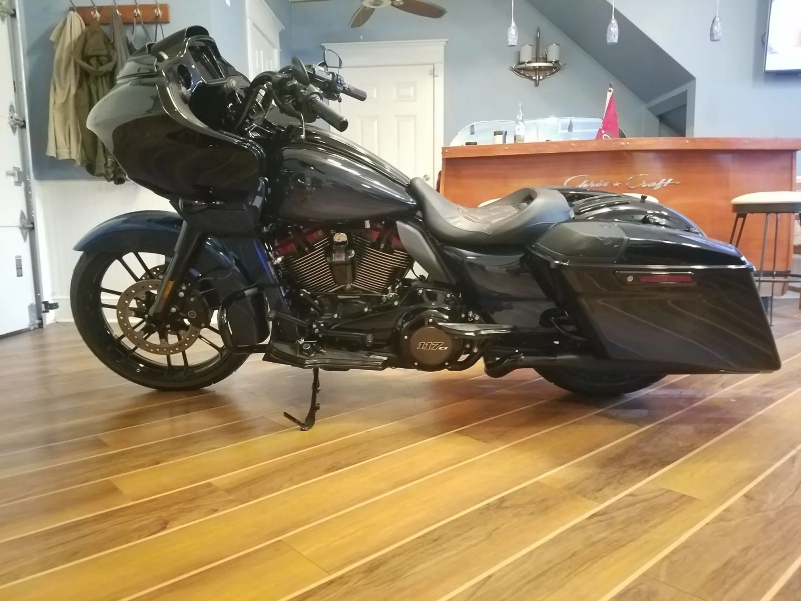 A black touring motorcycle parked indoors on a wooden floor.