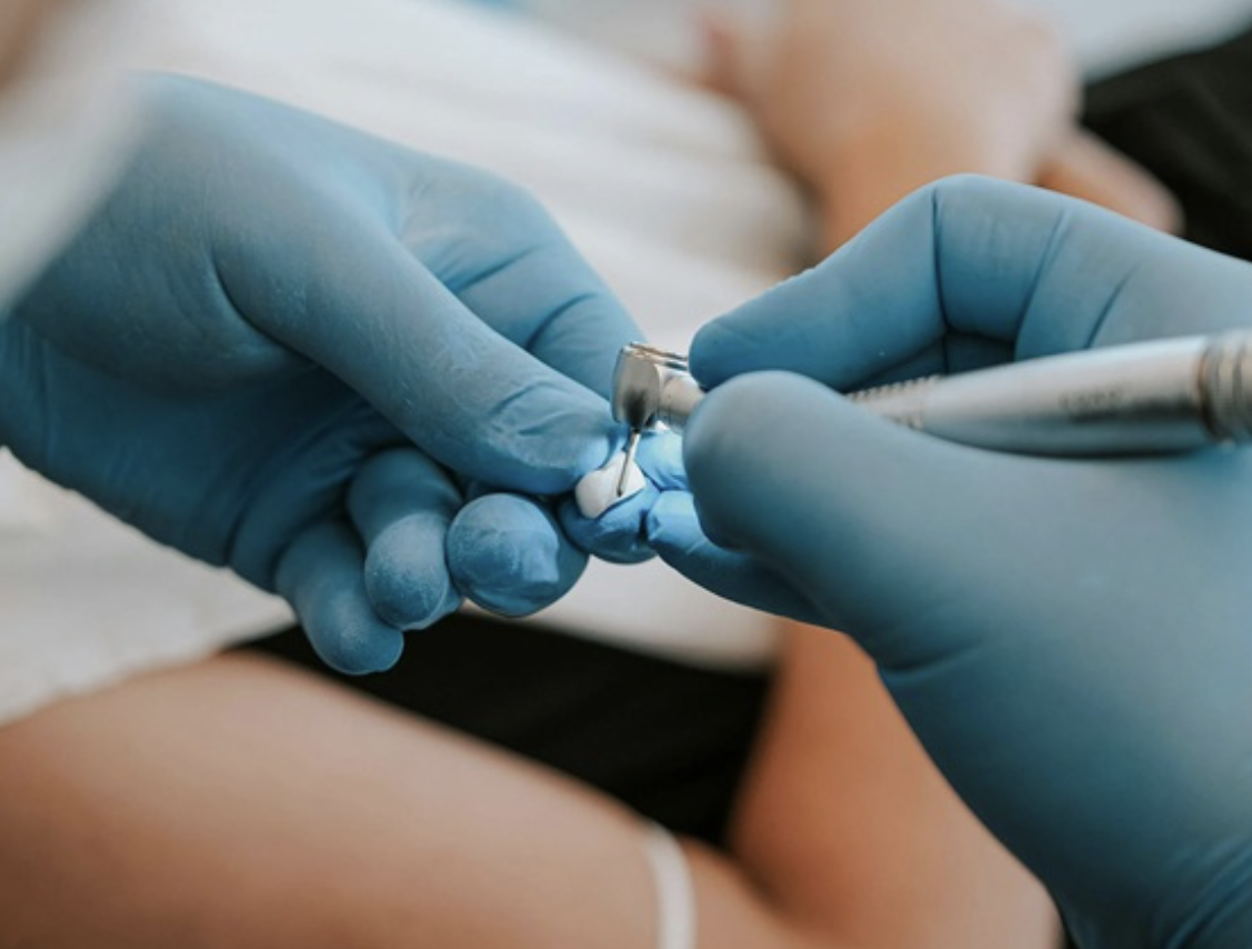 Close-up of a healthcare professional wearing blue gloves administering an injection or vaccination into a person's arm.