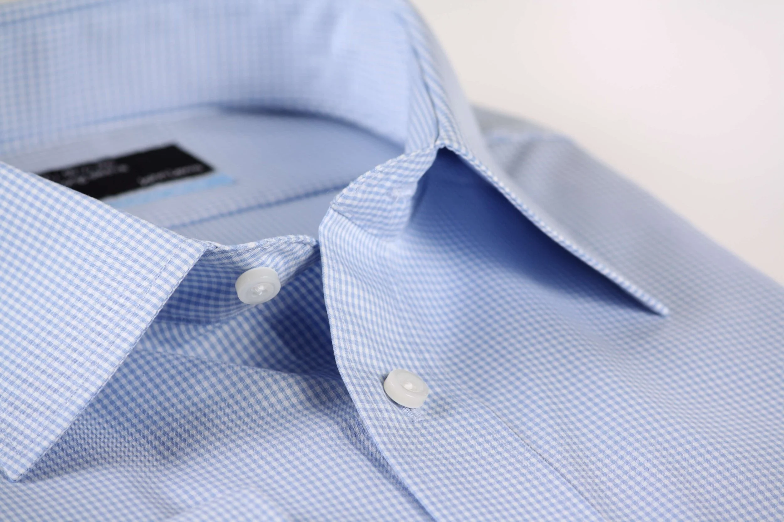 Close-up of a light blue, checkered dress shirt with a button-down collar.