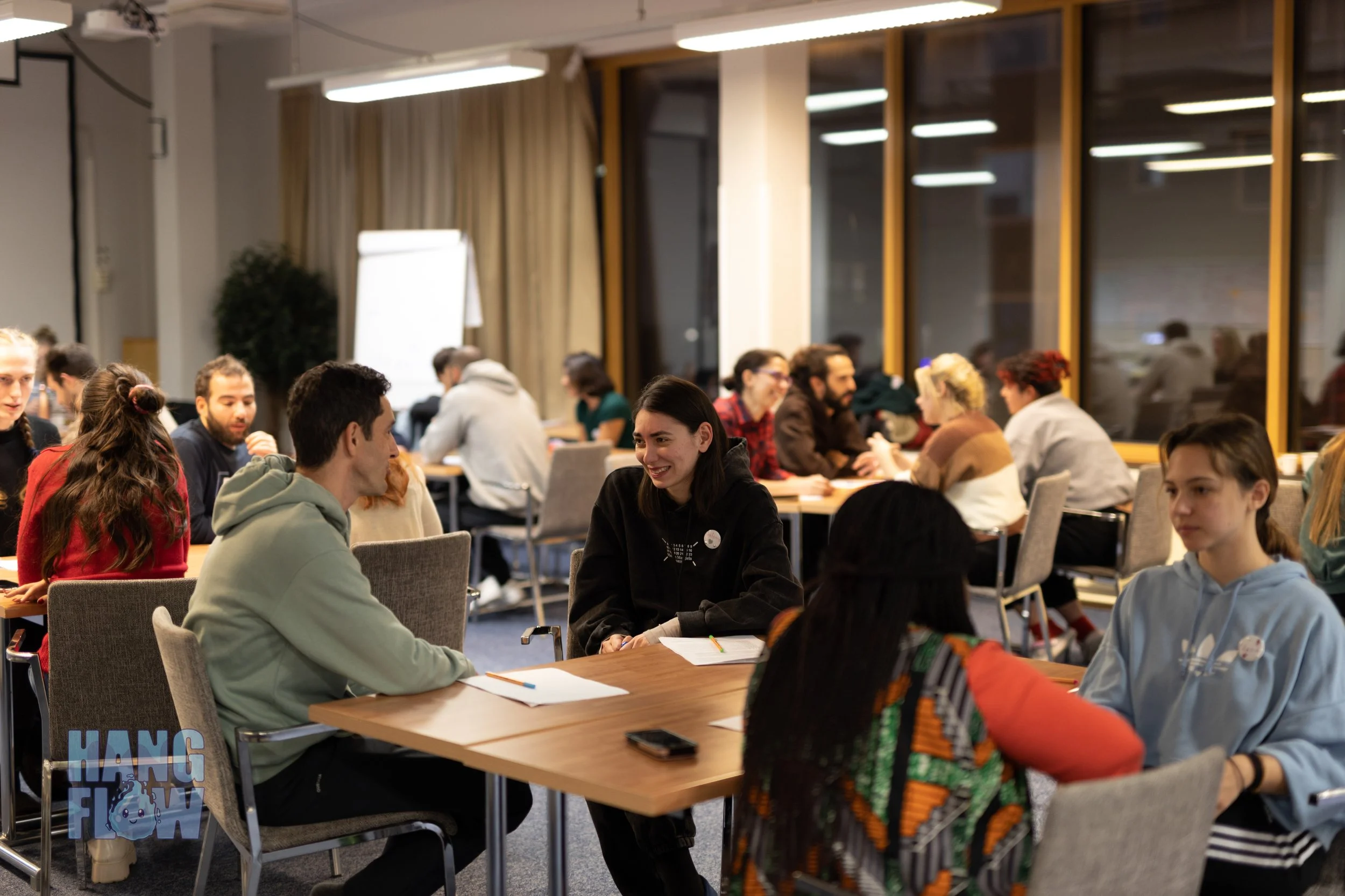 People sitting at tables in a conference room, engaged in discussions and conversations.