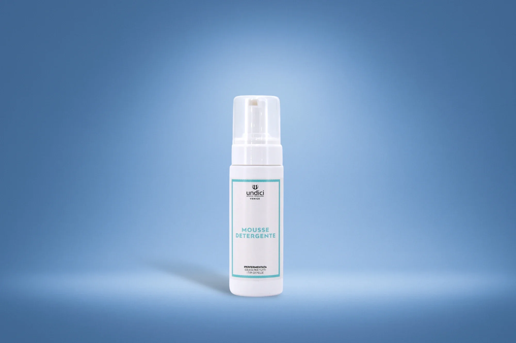 Flacone di mousse detergente bianco con etichetta azzurra, sfondo blu chiaro