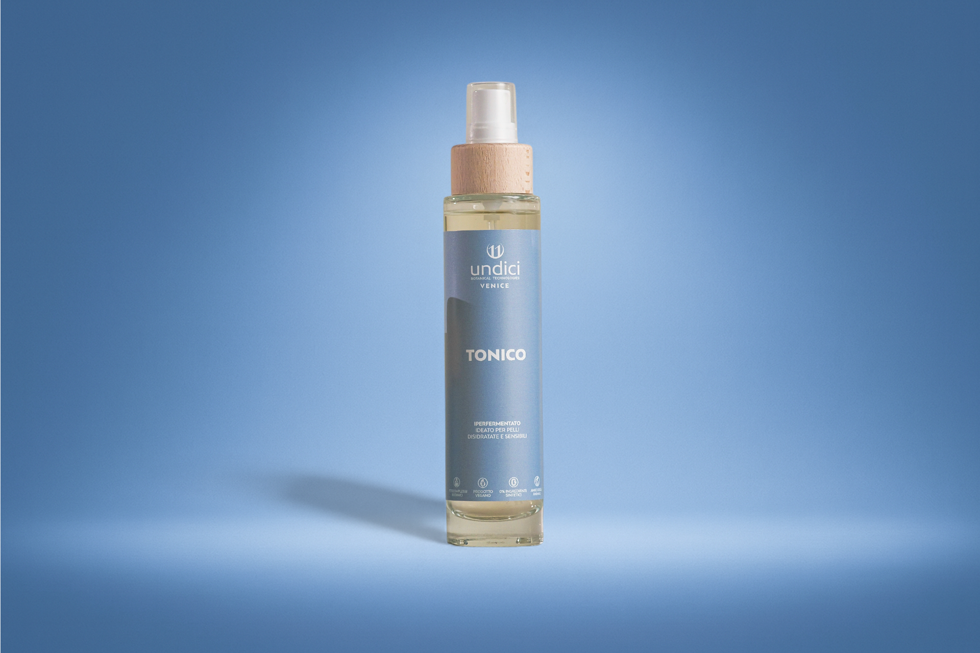 Bottiglia spray di tonico per la cura della pelle con etichetta blu, sfondo blu chiaro.