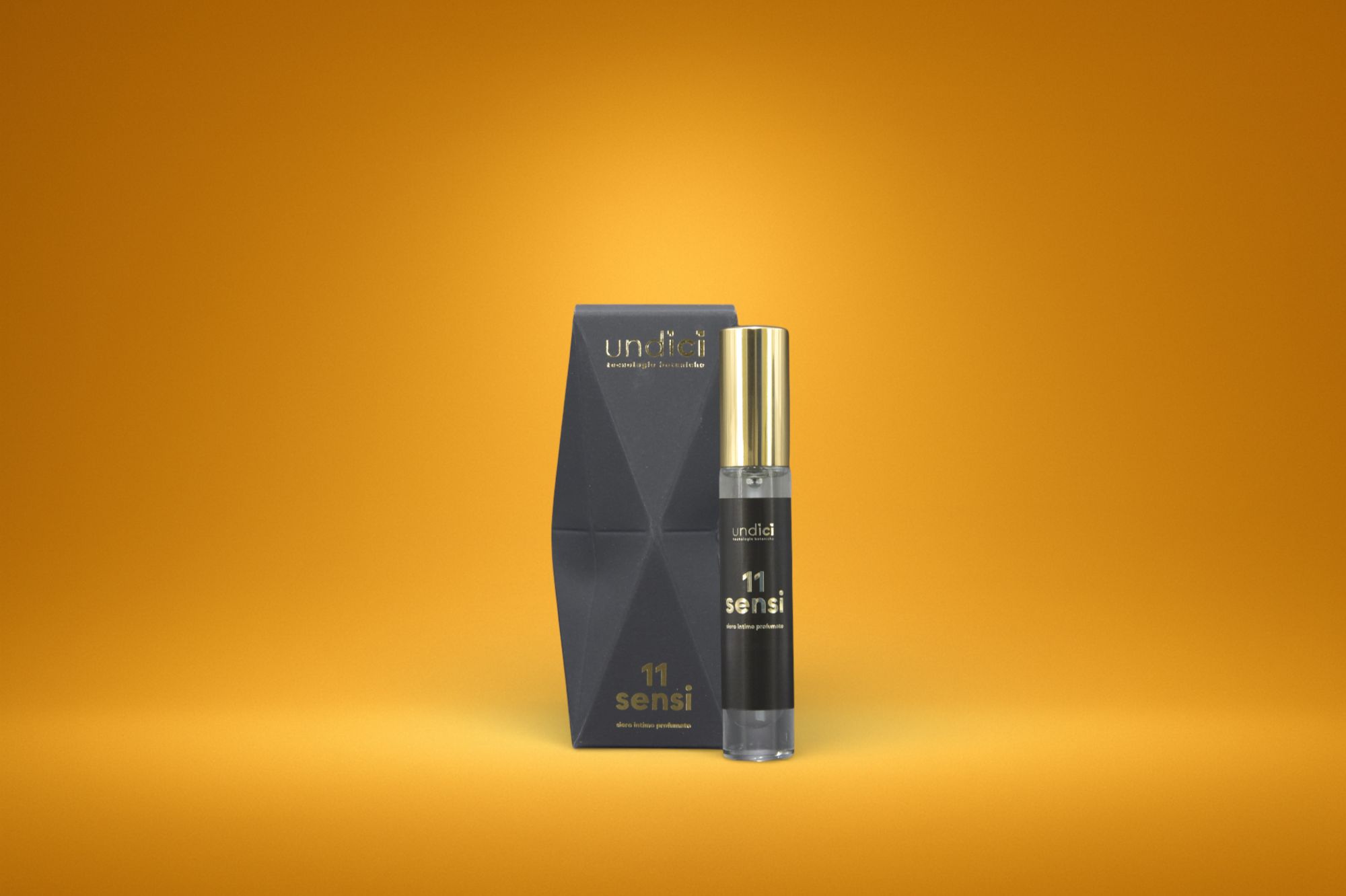 Un flacone di profumo con scatola sulla sinistra, entrambi con design nero e dettagli dorati, contro sfondo arancione.