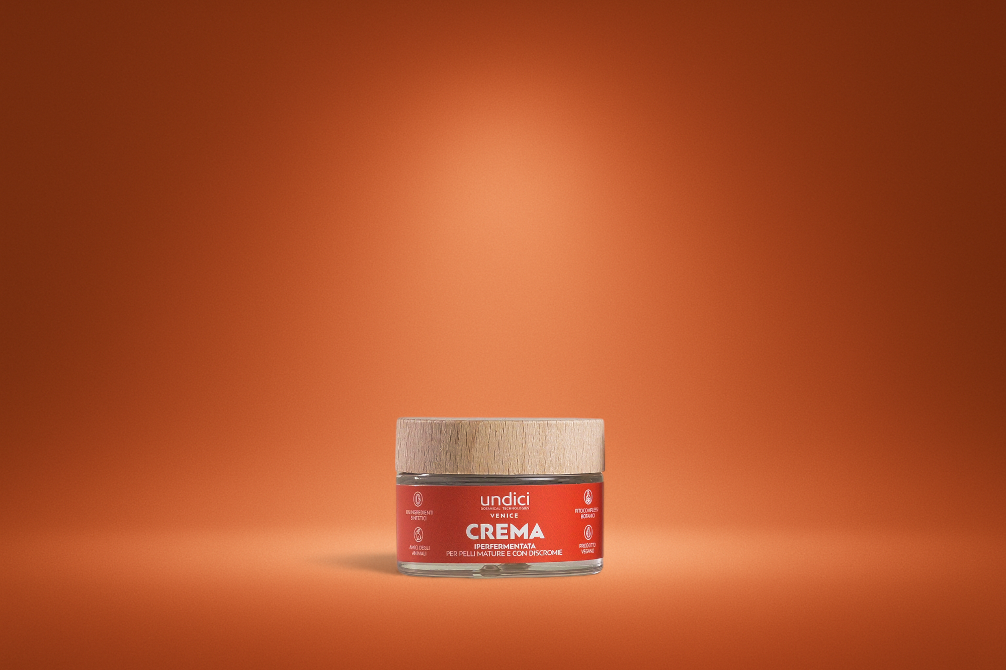 Contenitore di crema di texture uniforme con etichetta rossa, scritto 'undici Crema' con sfondo arancione