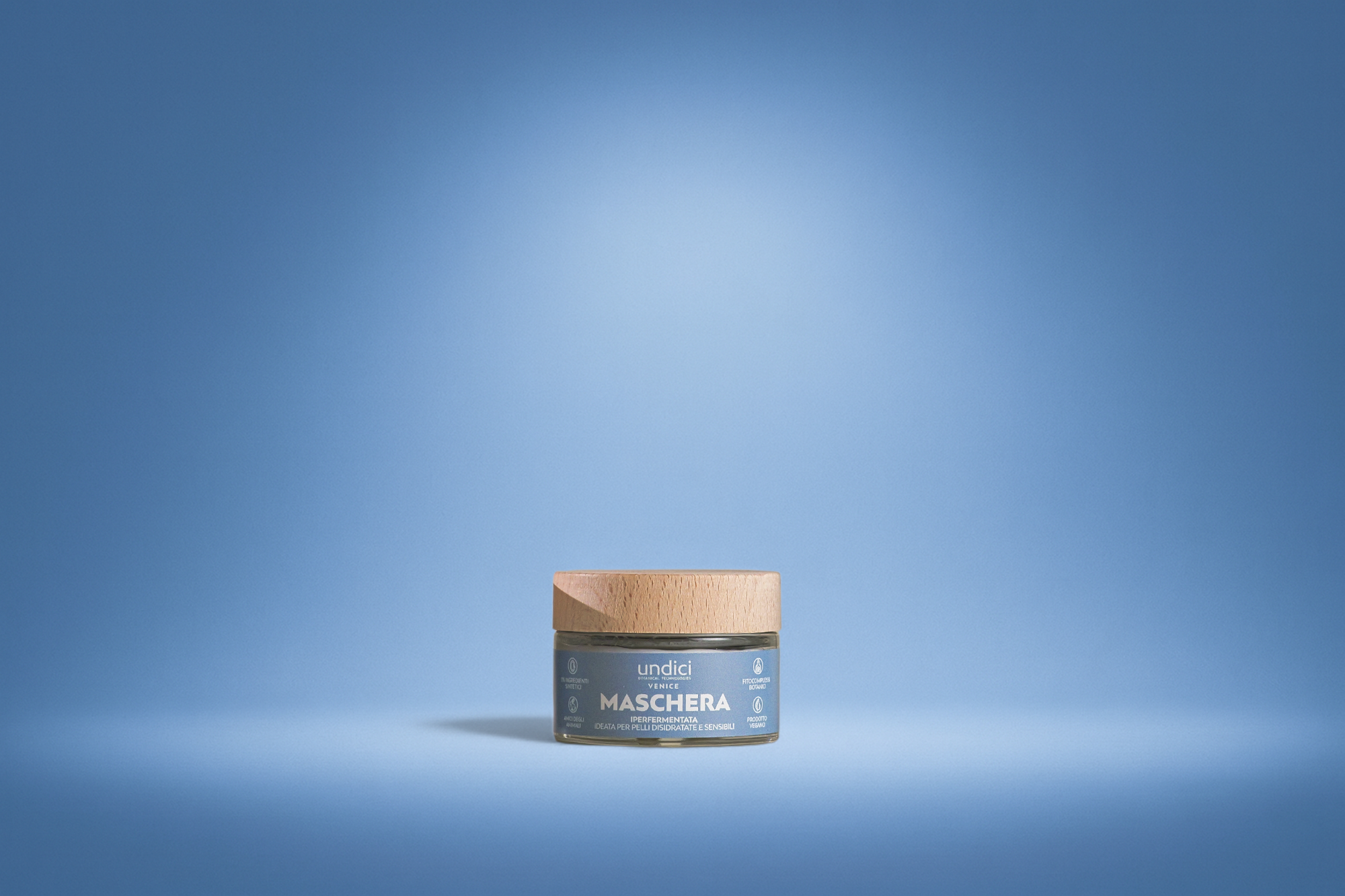 Crema viso in un barattolo con coperchio di resina e etichetta blu, su sfondo blu chiaro