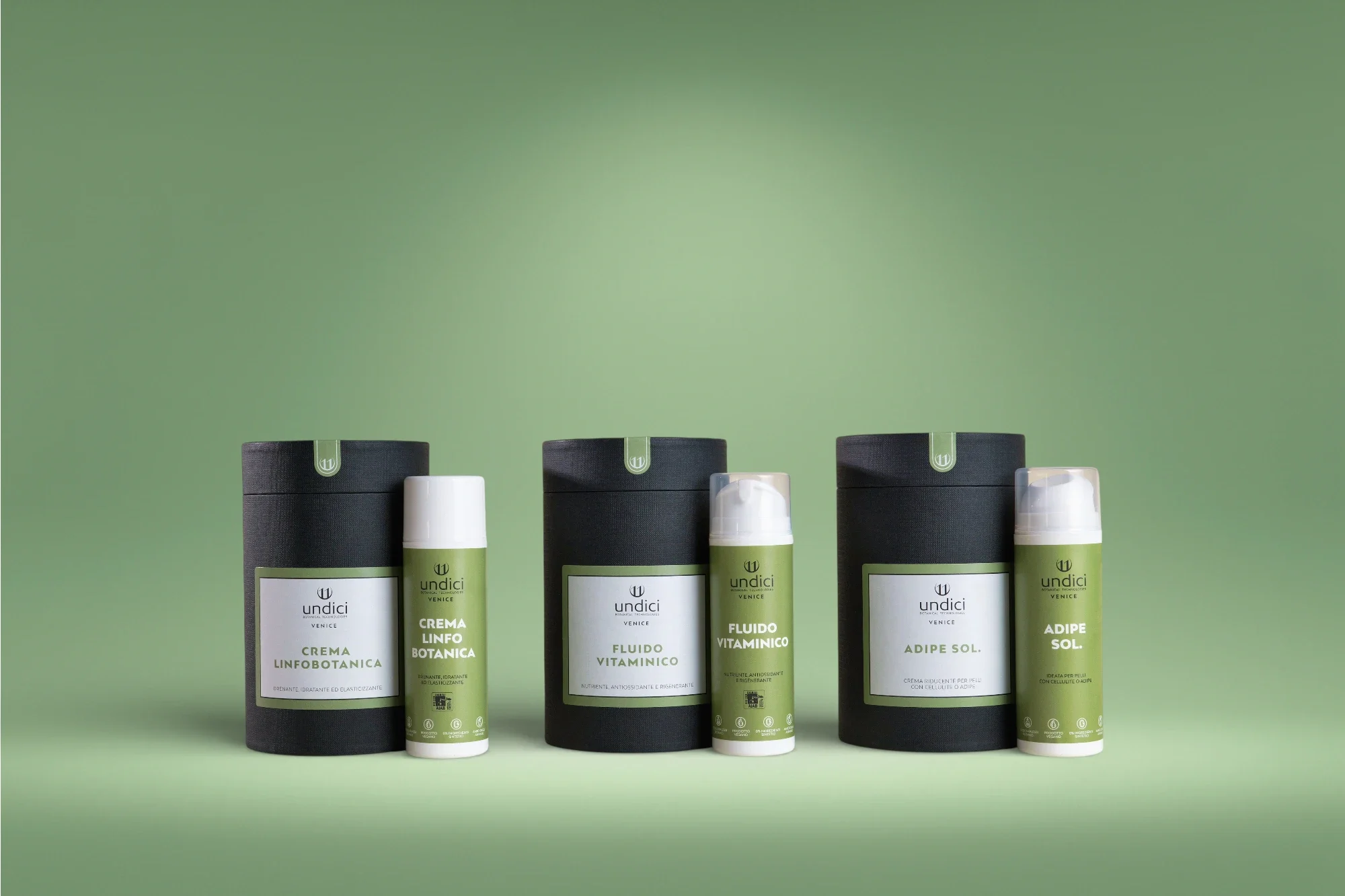 Set di tre prodotti di cosmetici vegani in contenitori verdi e neri con etichette bianche, disposti su uno sfondo verde.