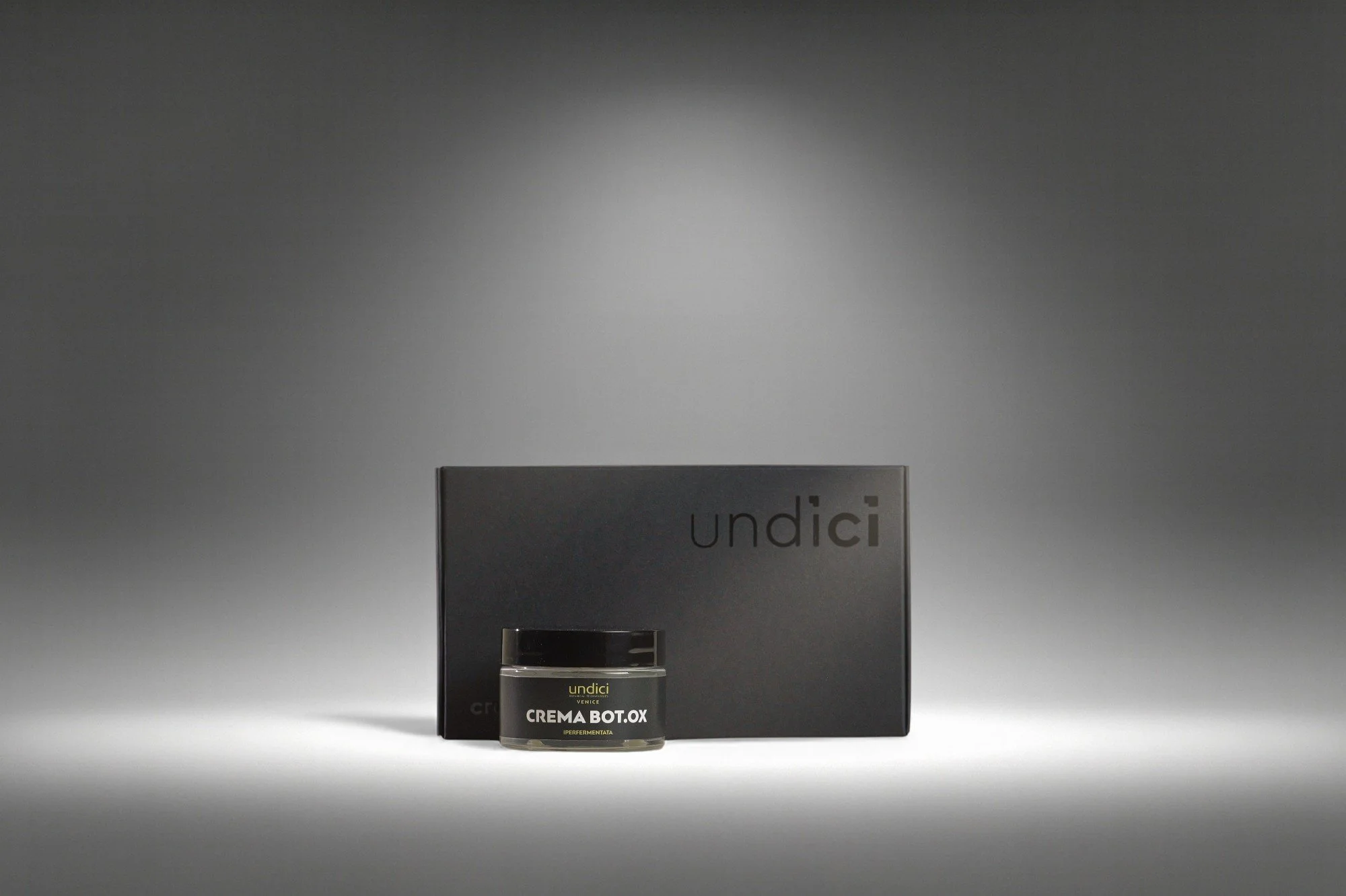 Prodotto di bellezza in un barattolo e confezione nera sullo sfondo grigio scuro.