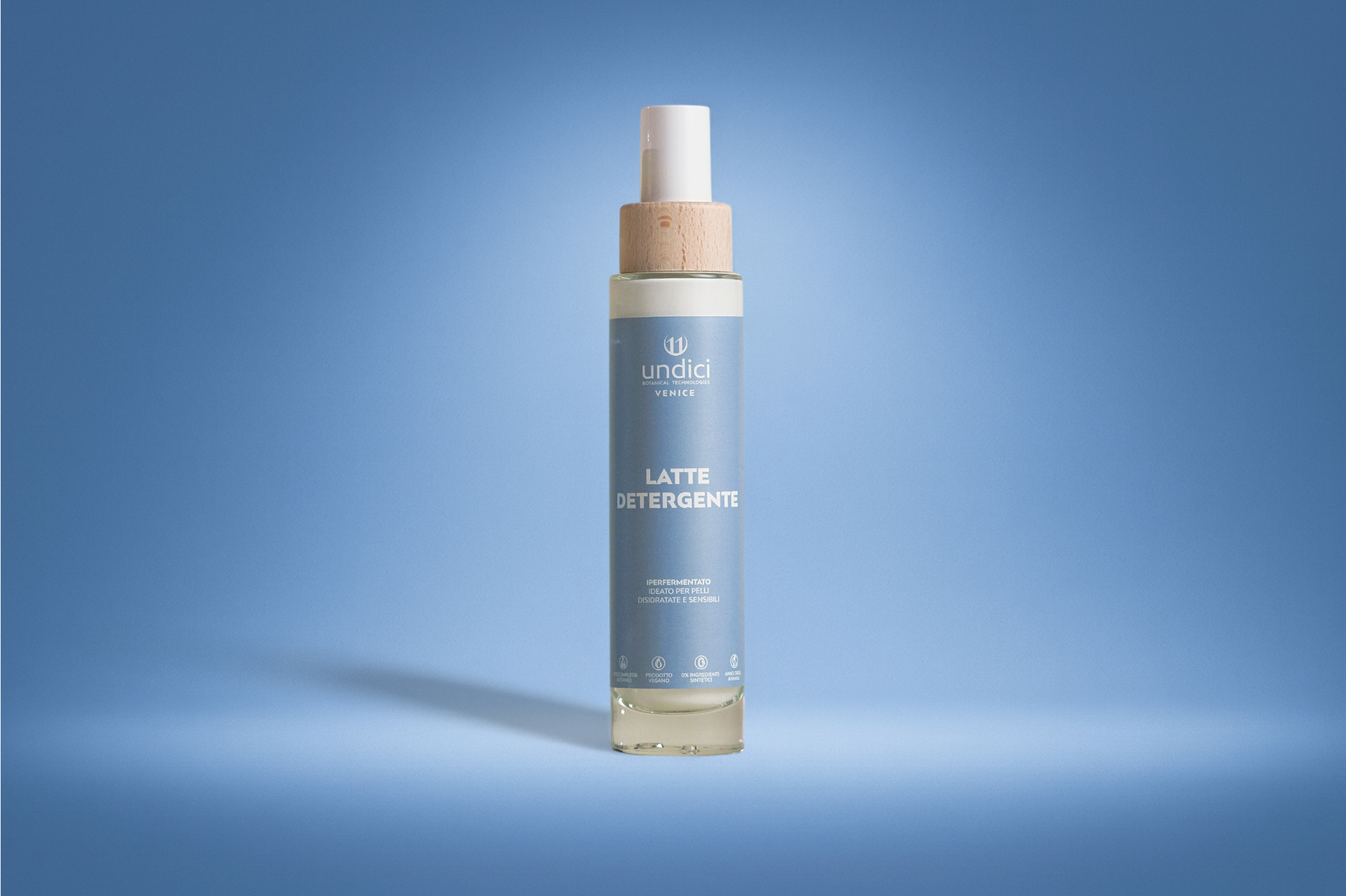 Flacone di detergente con etichetta blu e tappo bianco, sfondo blu, ombra proiettata sulla sinistra.