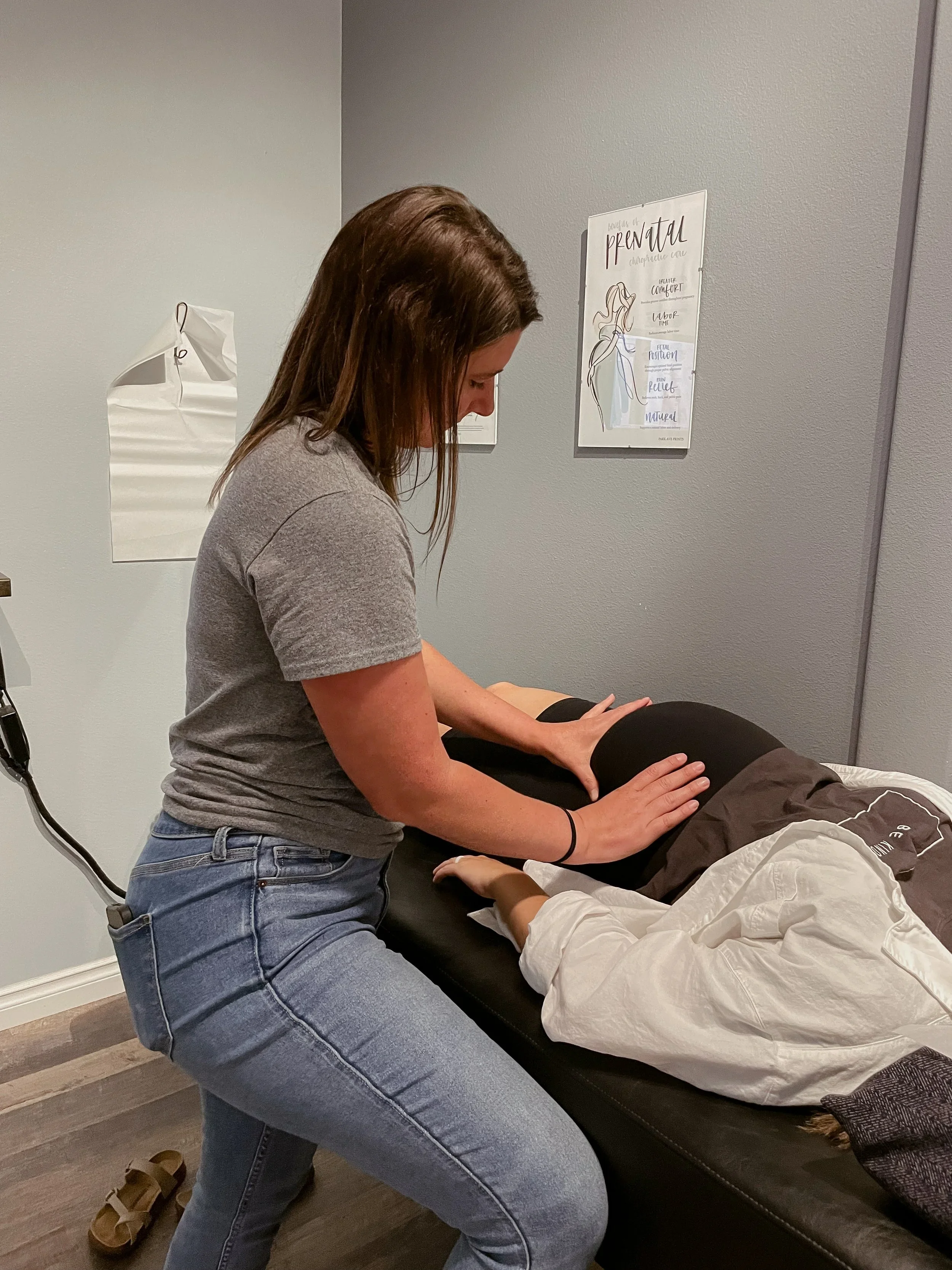 A woman giving a massage to a person lying face down on a massage table in a spa or massage therapy room.