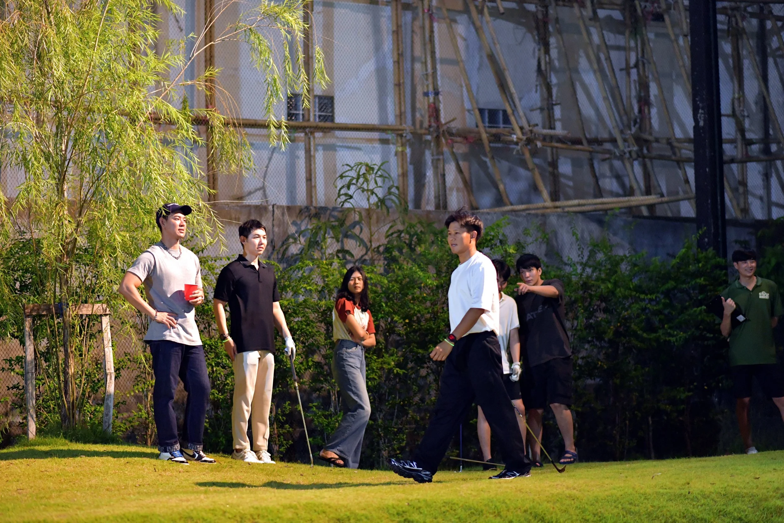 Group of young people playing golf on a lush outdoor course during daytime.