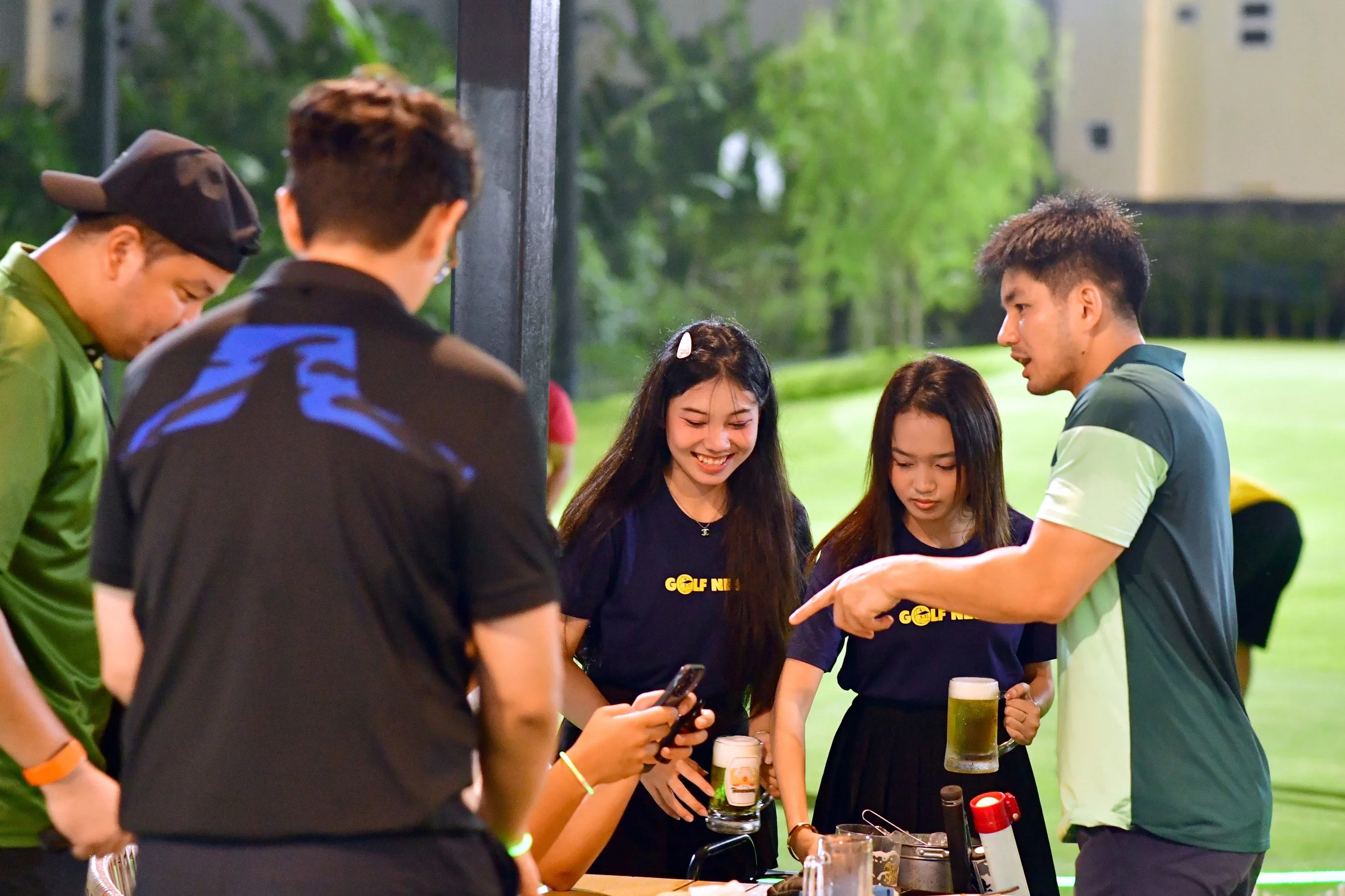 Group of young people at a golf event enjoying drinks and chatting outdoors