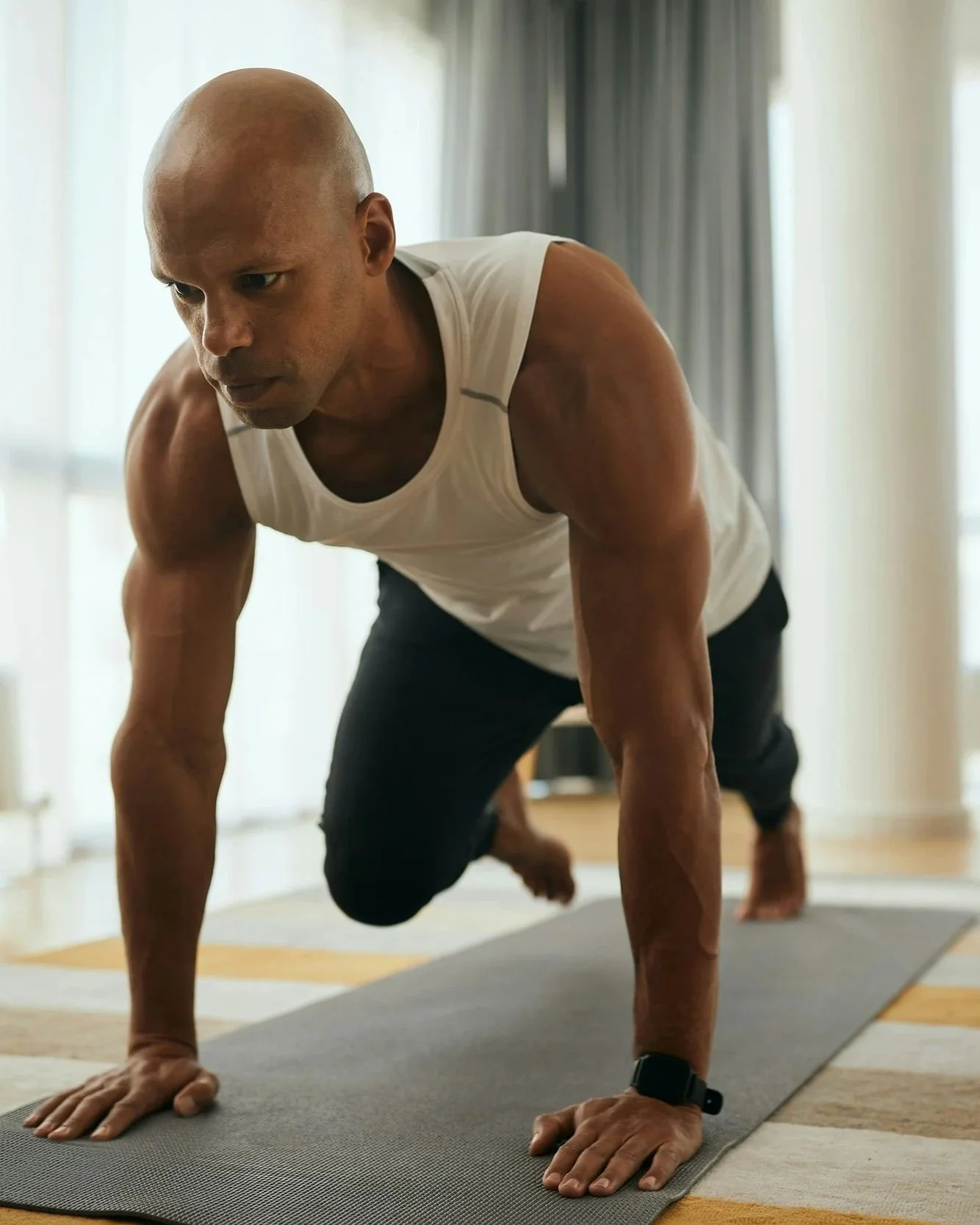 A man doing a yoga plank pose on a yoga mat indoors.