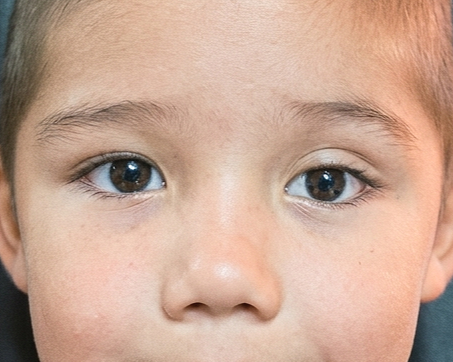 Primer plano del rostro de un niño con ojos marrones y piel clara.