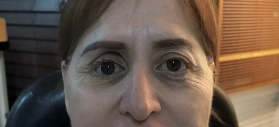 Primer plano de una mujer con cabello castaño y ojos grandes, en un ambiente interior.