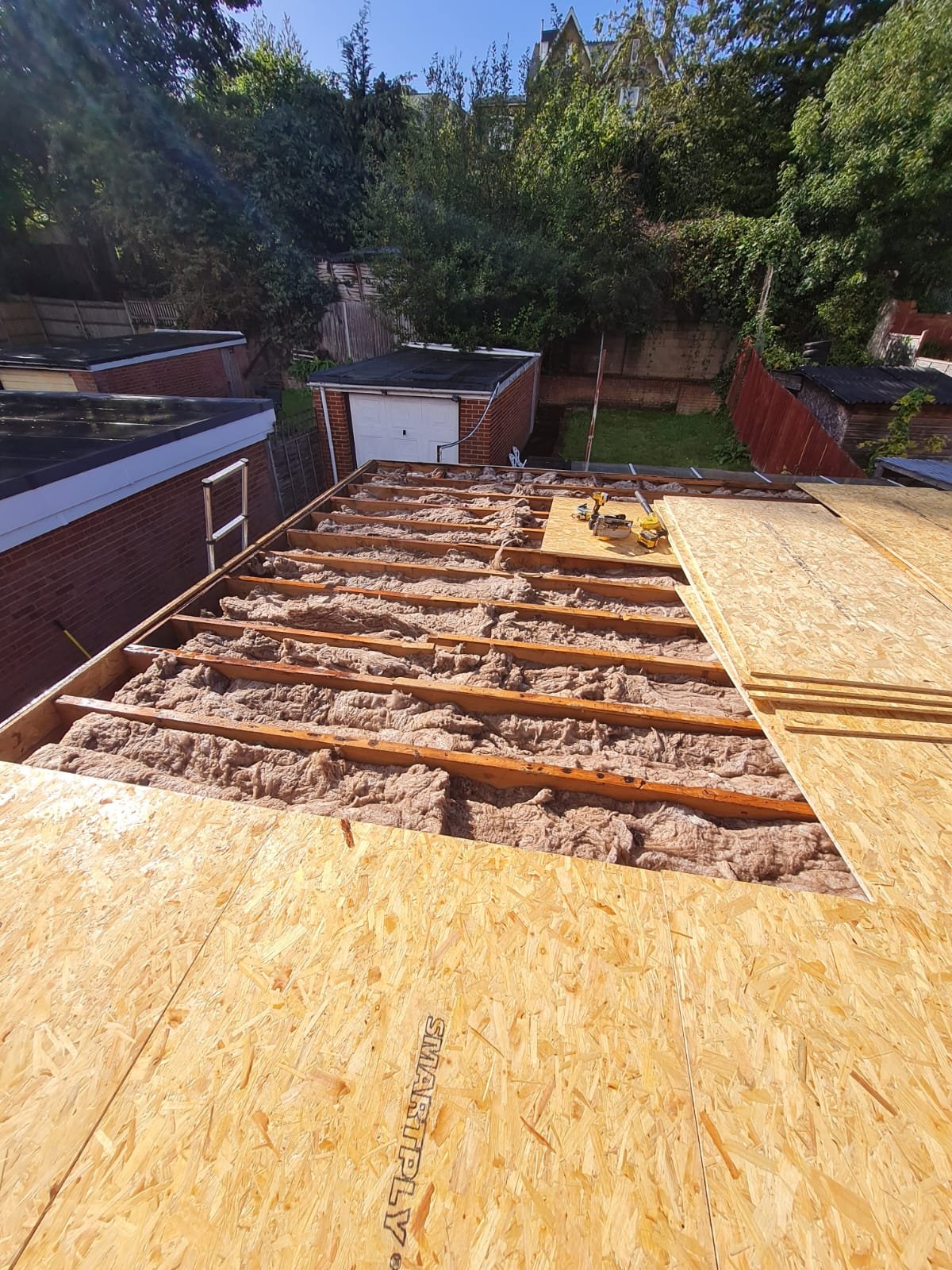 Flat roof deck stripped to timber joists and insulation during a residential roof replacement