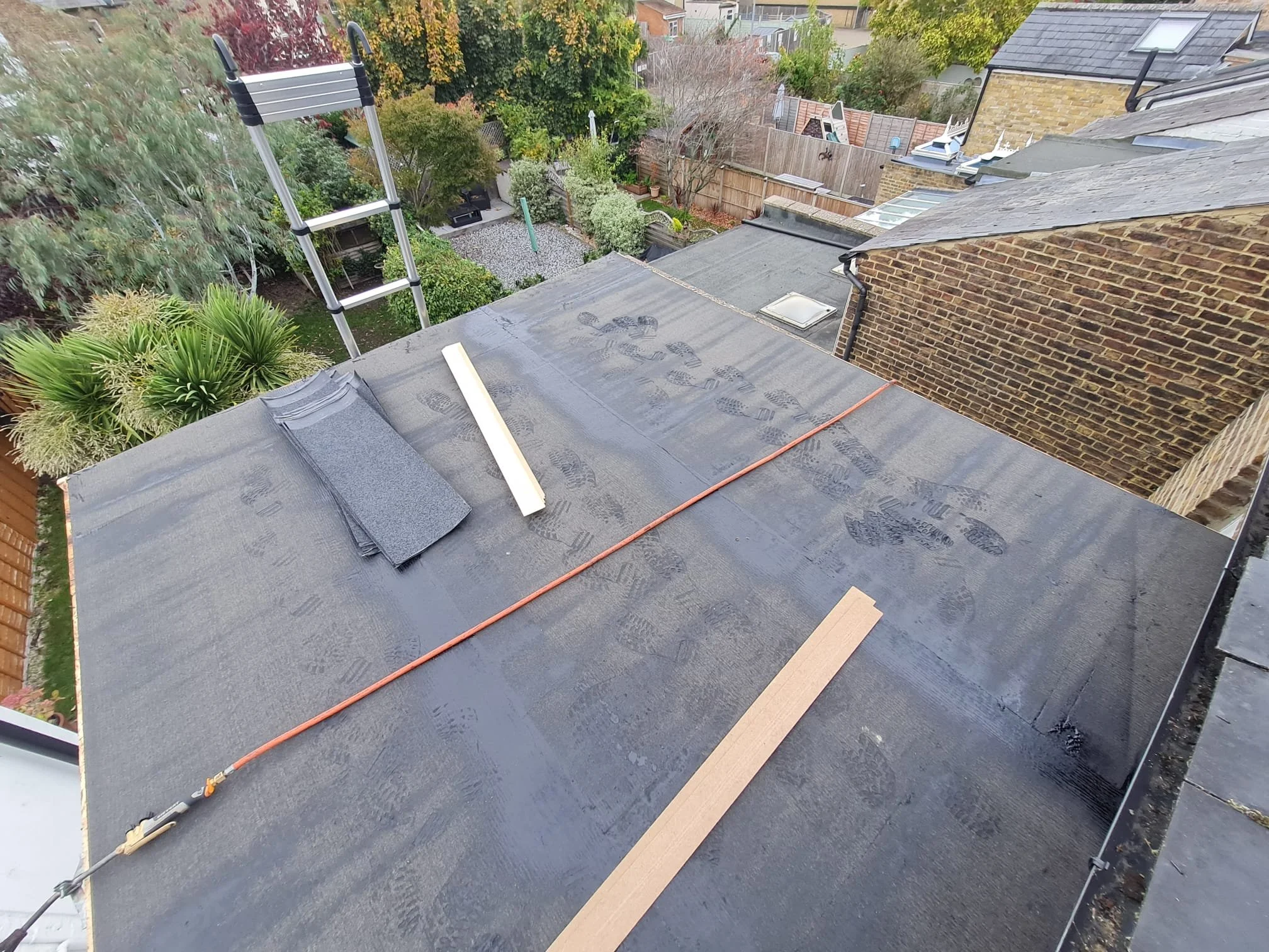 Flat roof deck stripped to timber joists and insulation during a residential roof replacement