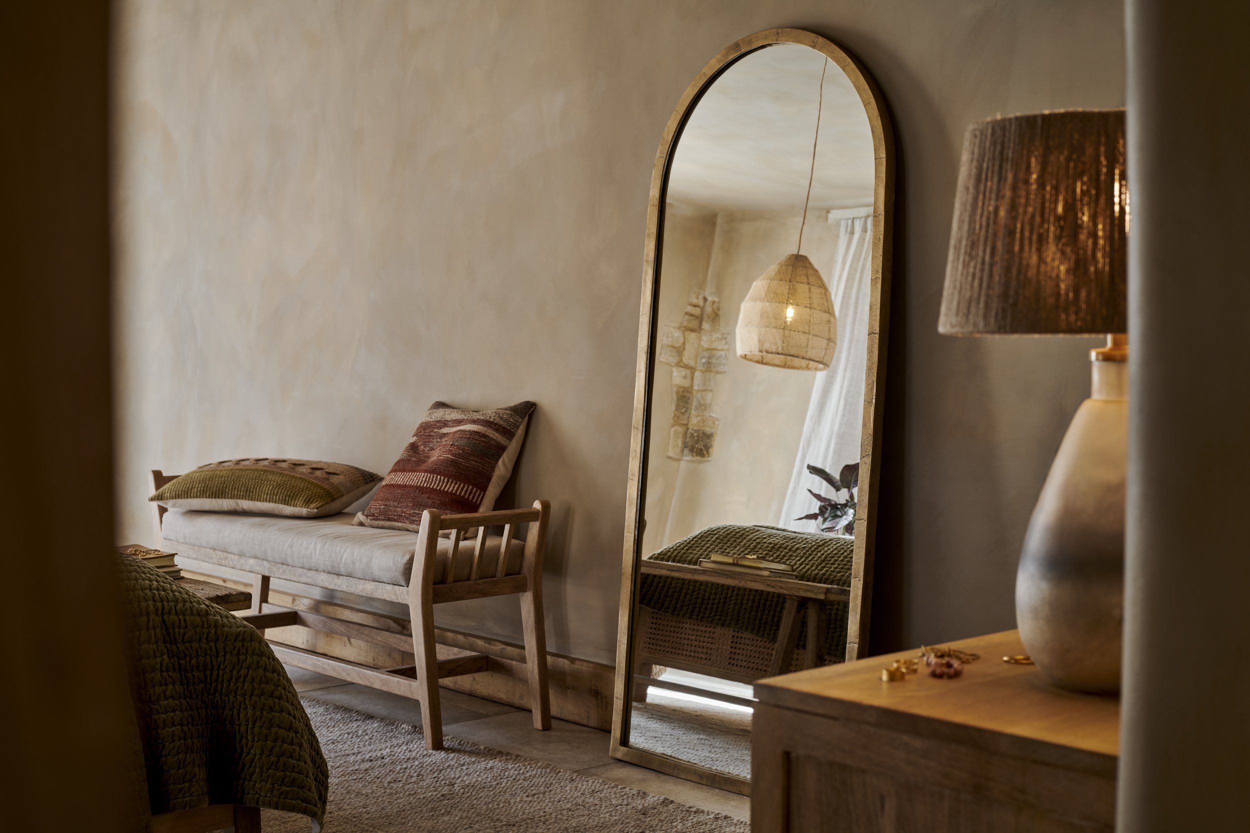 Bench with a mirror leaving aginst a wall with lighting in reflection