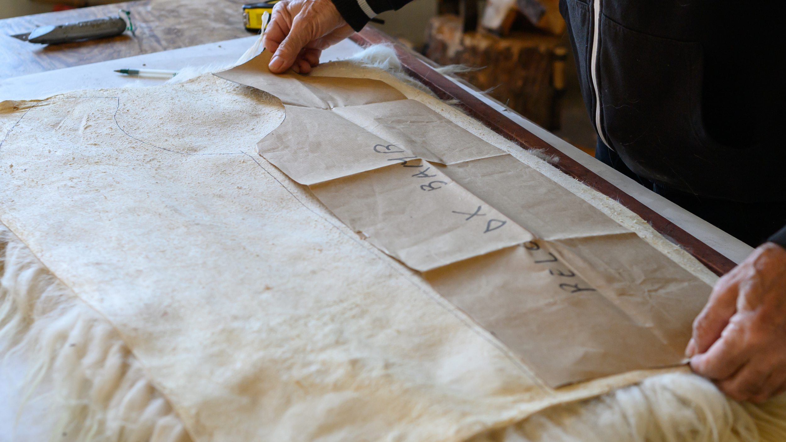Person measuring sheepswool on table with ruler