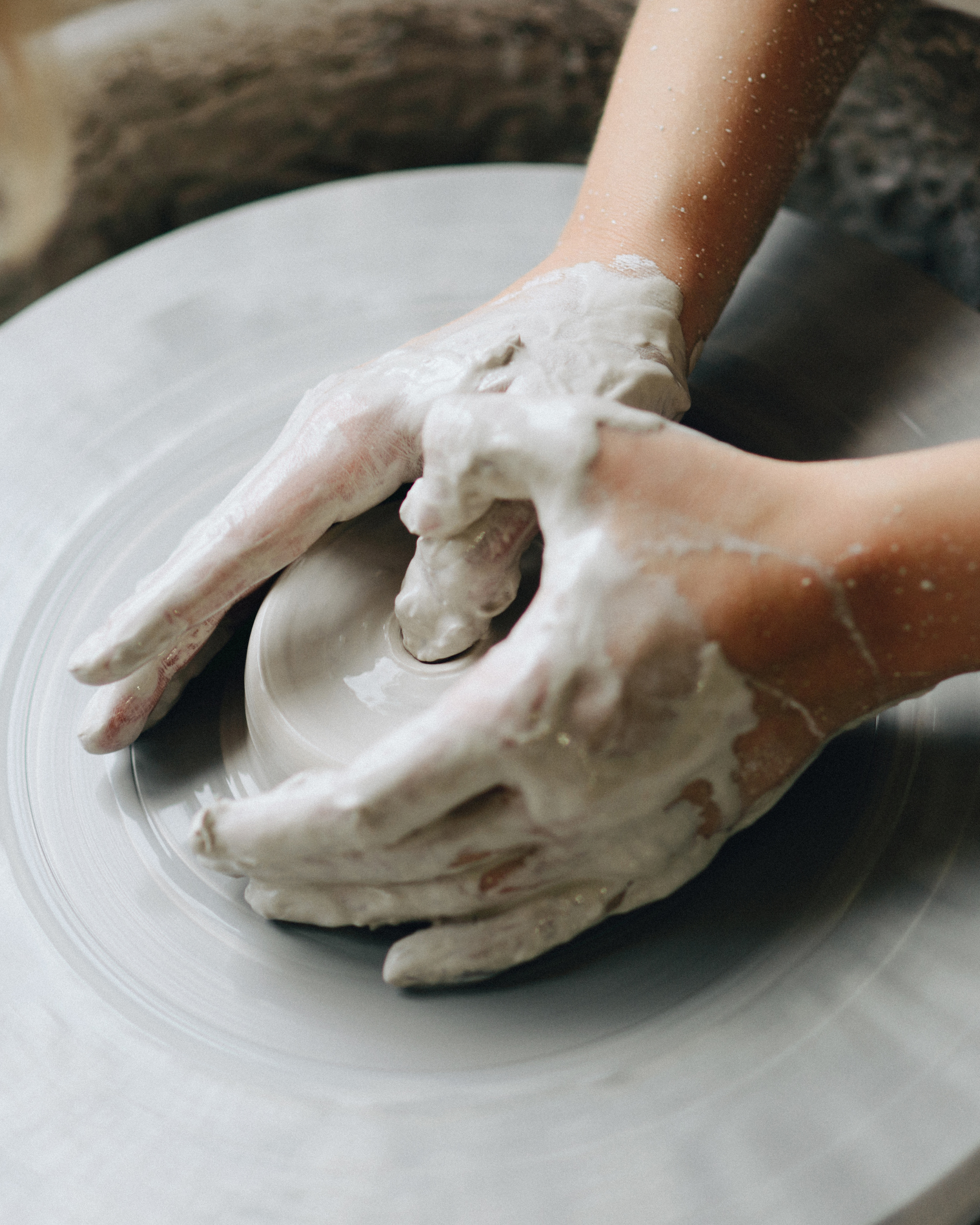 Person shaping clay on a pottery wheel with soapy hands.