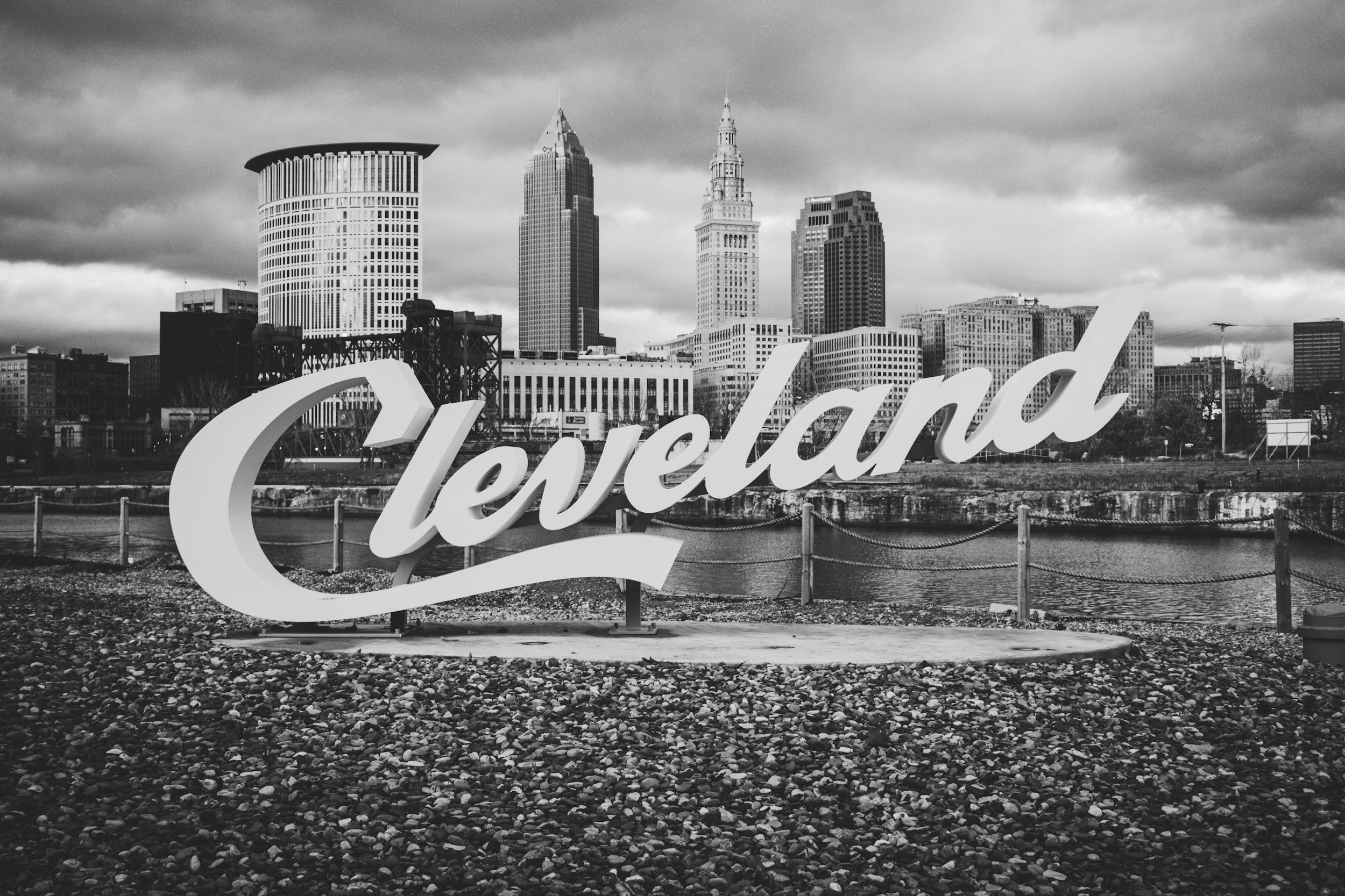 Black and white photo of Cleveland's skyline with a large sign reading 'Cleveland' in front of the cityscape.