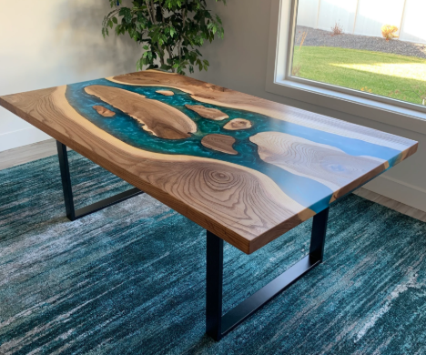 Wooden table with blue resin river design, indoors near a window with a green plant in the background.