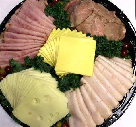 Assorted sliced deli meats, cheese slices, and green parsley garnishes on a platter.