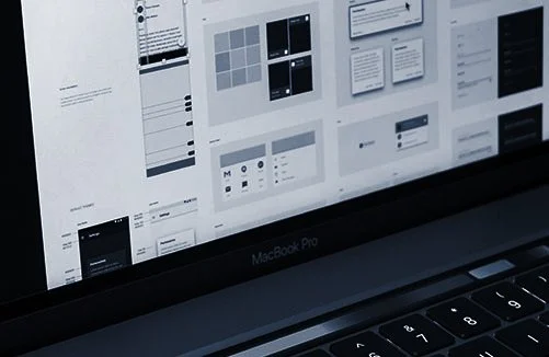 Close-up of a MacBook Pro laptop screen displaying various app design templates and interface layouts.