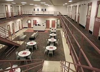 Empty dining area with tables, chairs, and a mezzanine level in the background.