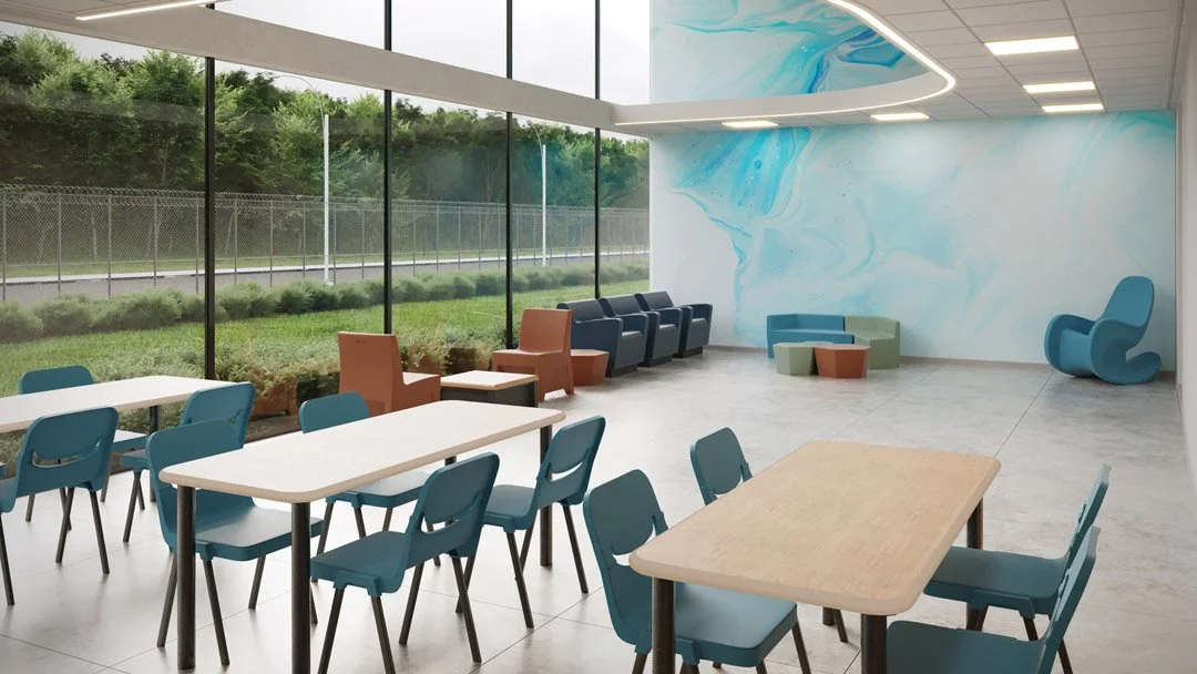 Modern indoor lounge area with colorful chairs and tables, large floor-to-ceiling windows overlooking green outdoor landscape, and abstract blue and white wall art.