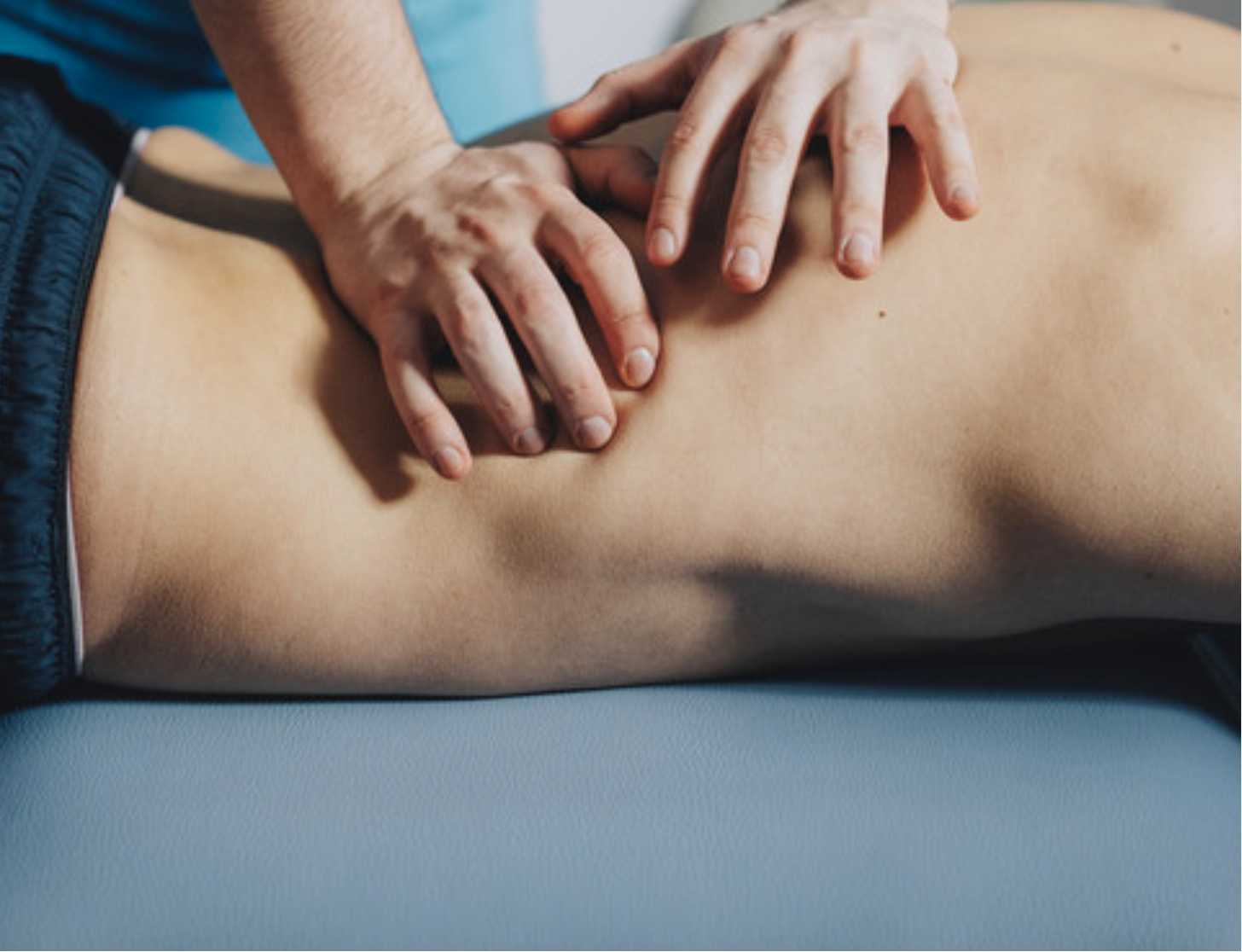 A person receiving a back massage from a massage therapist in a clinical setting.