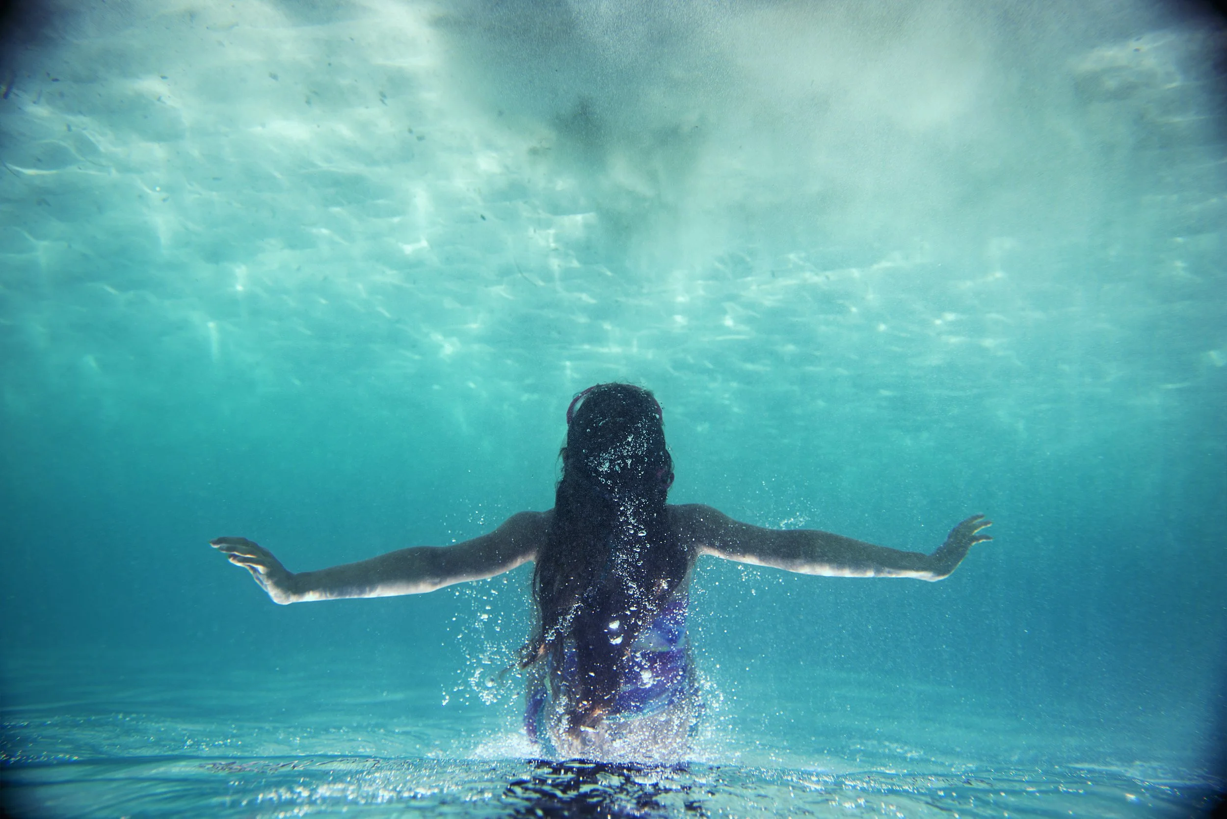 Person swimming underwater with arms extended, water surrounding them.