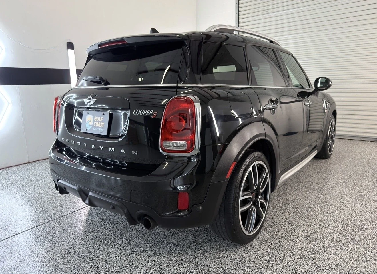 Black Mini Countryman Cooper S SUV inside a garage, showing rear view with Gulf Coast Auto Studio license plate.
