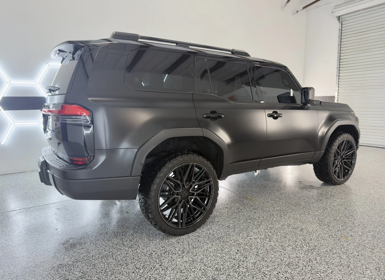 A matte black SUV parked indoors with black alloy wheels, tinted windows, and a modern angular design.