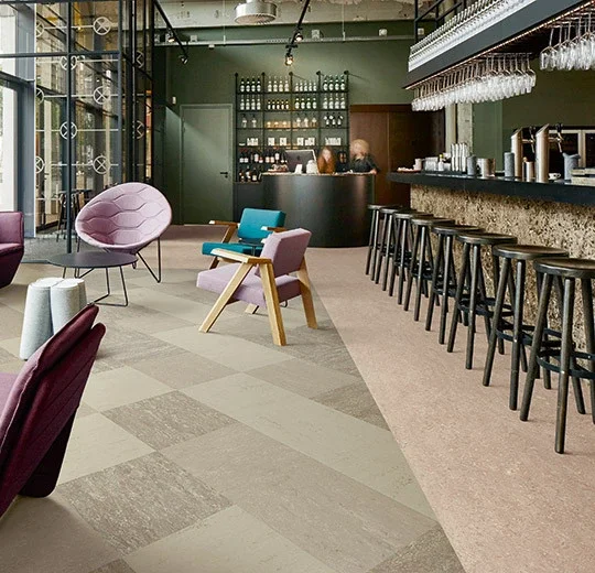 Modern lounge with colorful lounge chairs, bar stools at a marble bar, and a barista counter in the background.