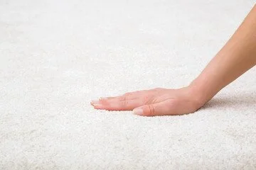 Person's hand pressing down on white sand.