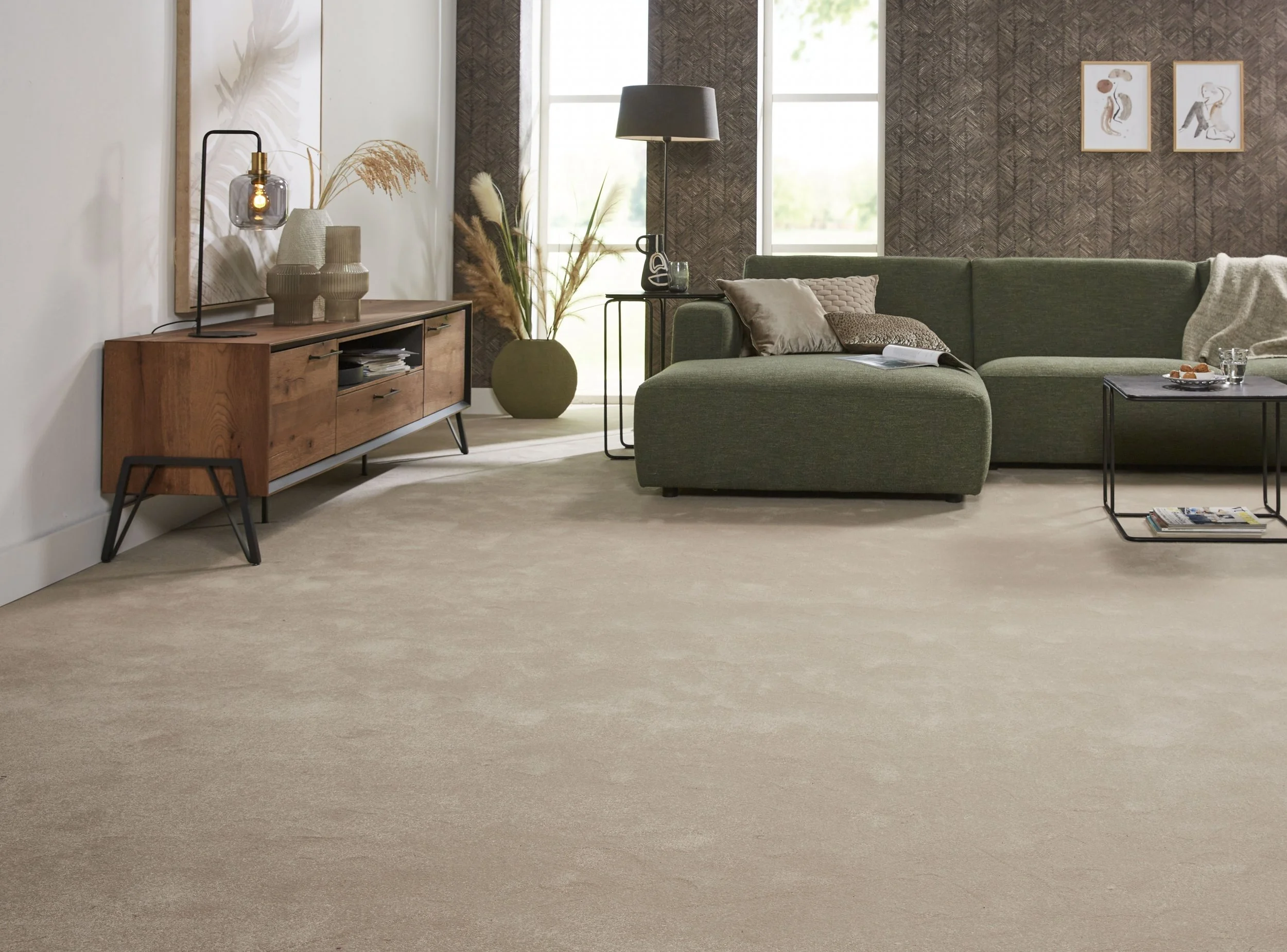 Living room with beige carpet, green sofa, wooden media console, decorative vases, table lamps, potted plants, wall art, and a window.