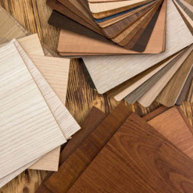 Various wood veneer samples in different shades and grains arranged on a wooden surface.