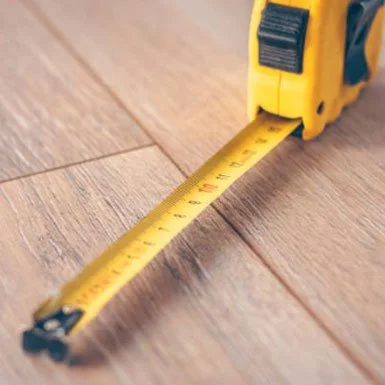 Close-up of a yellow tape measure extended on a wooden surface.