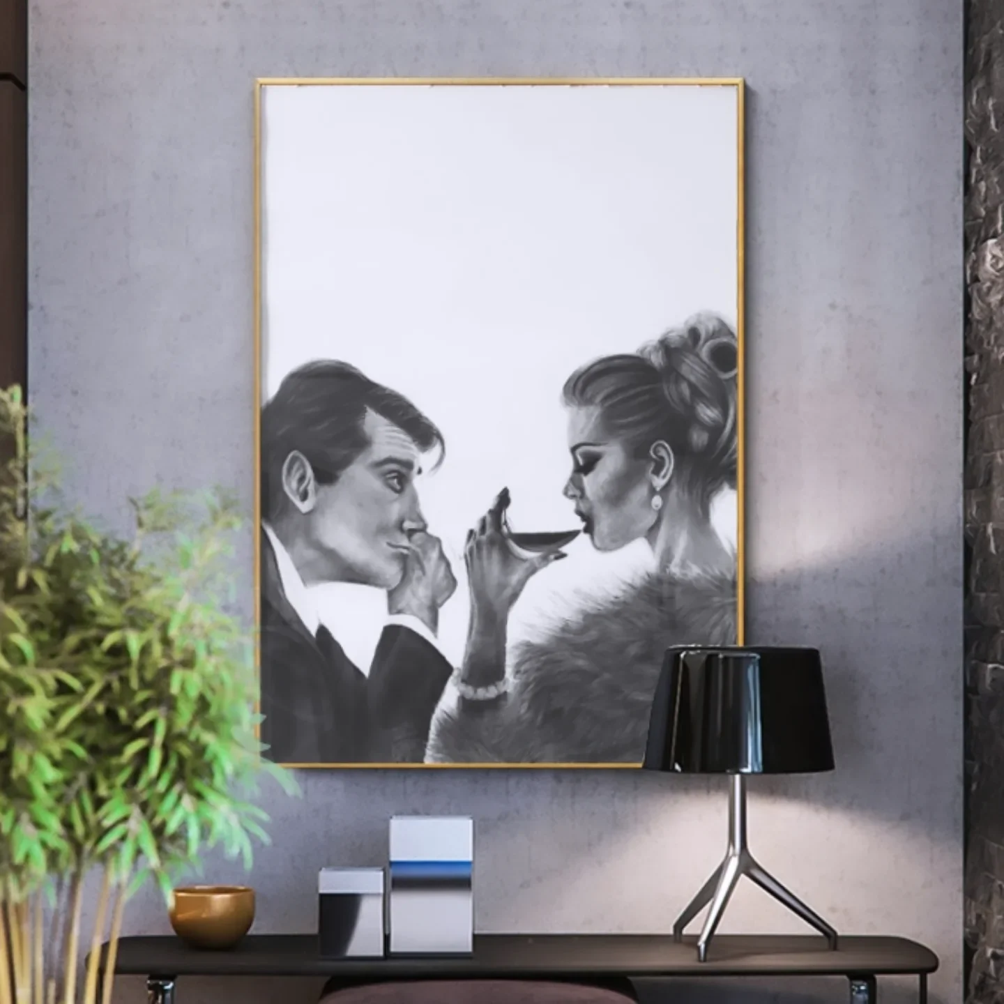 A black and white painting of a man and woman facing each other. The man holds a spoon near the woman's lips, and the woman gazes at him, both wearing elegant clothing. The scene is framed in gold and hung on a grey wall, with a black lamp and some decorative objects on a table in front.
