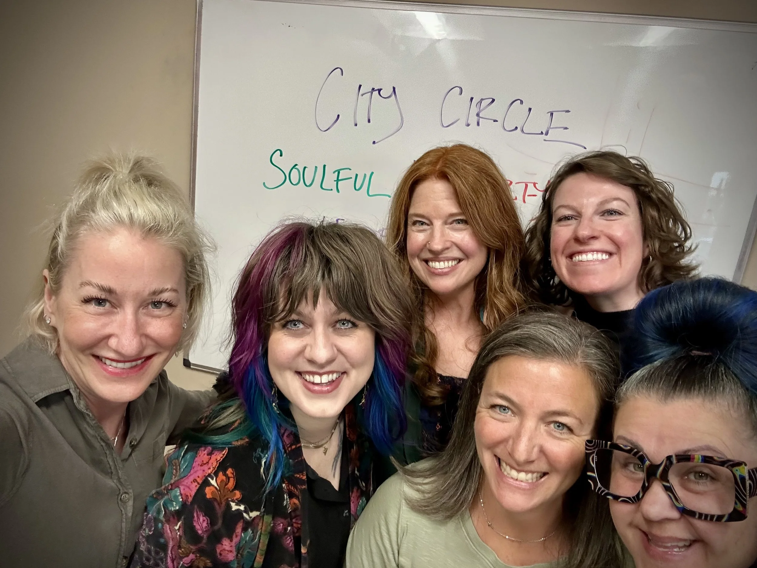 Group of women smiling for a selfie in front of a whiteboard with the words 'City Circle' and 'Soulful' written on it.