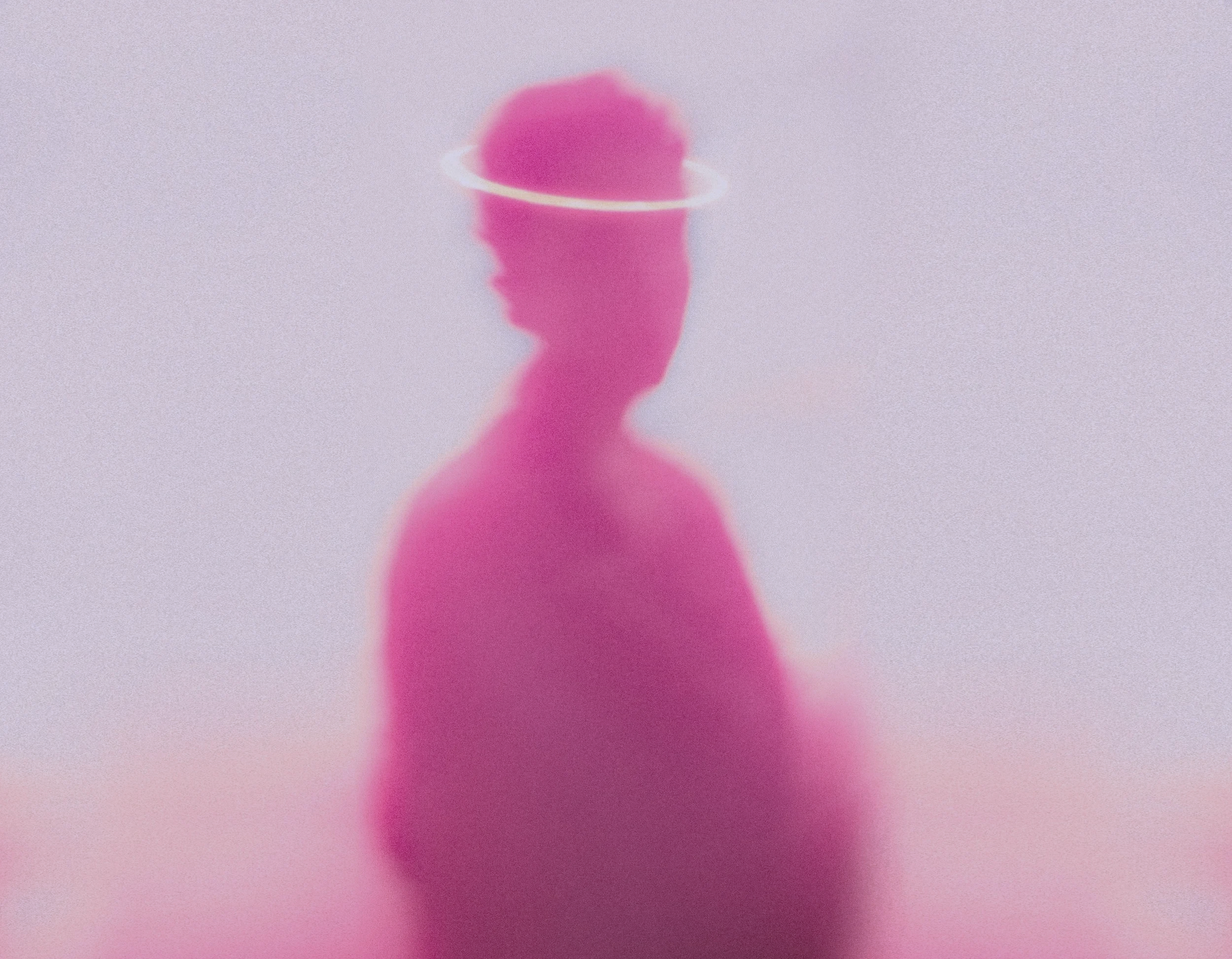 A pink silhouette of a person with a halo around their head, set against a light background, creating a soft, ethereal effect.