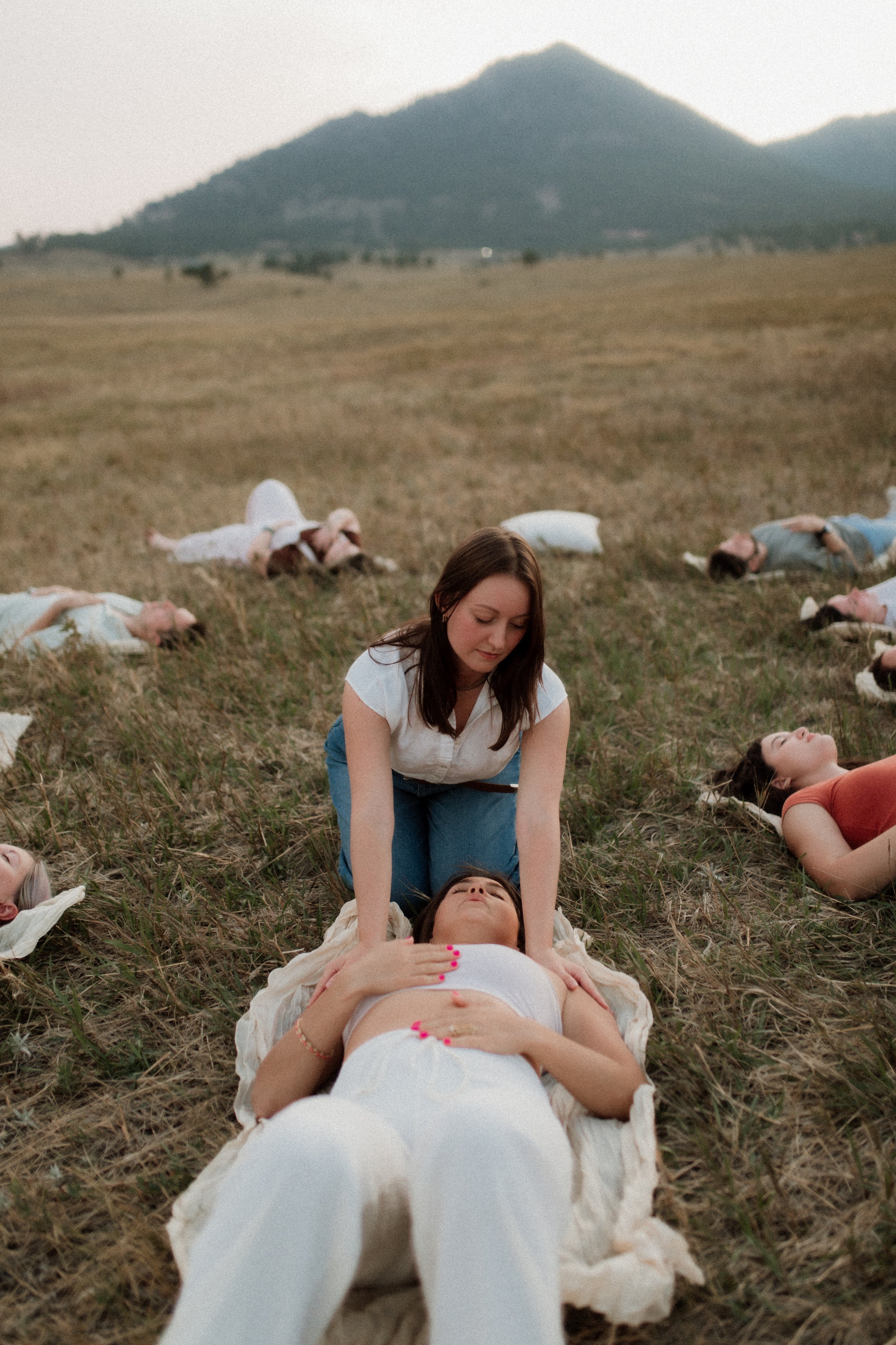 People lying on the grass in a field doing breathwork