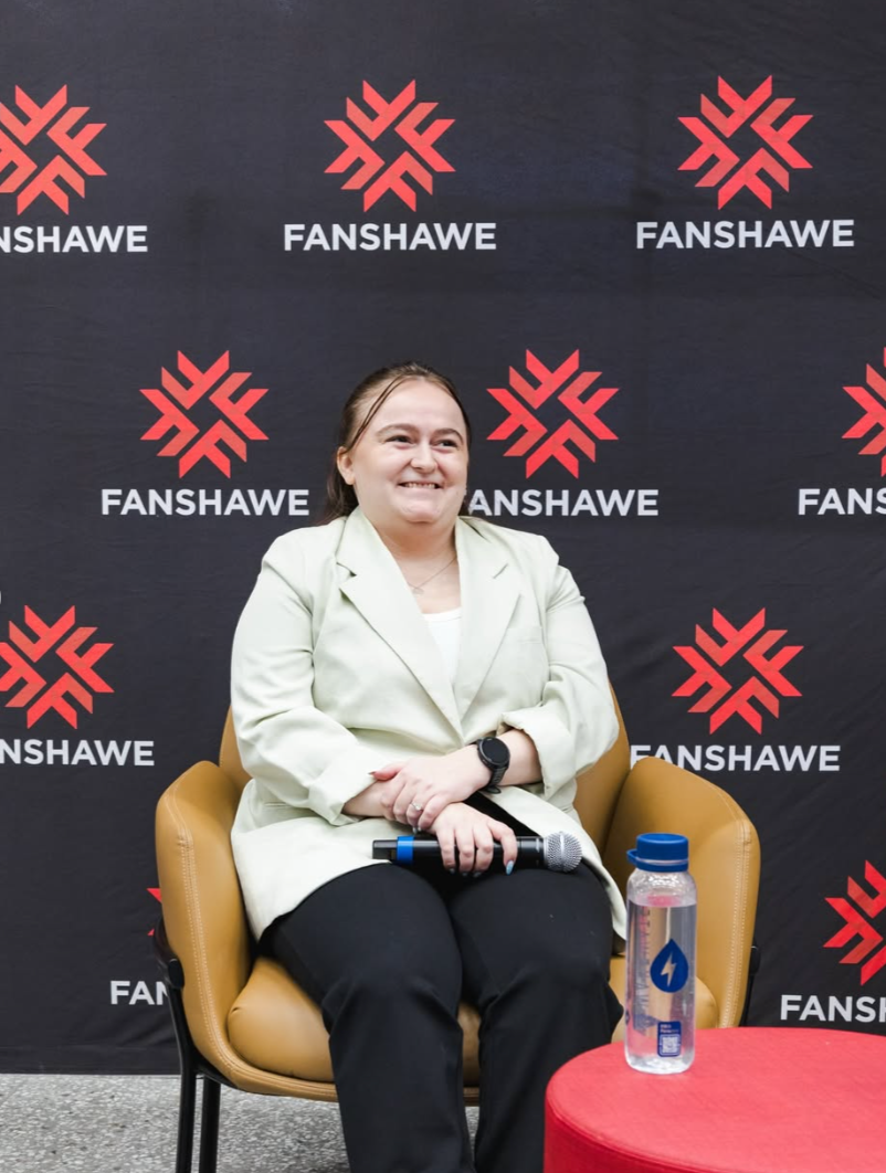 Ashley Rowe speaking at a marketing workshop event at Fanshawe College, holding a microphone during a live session.